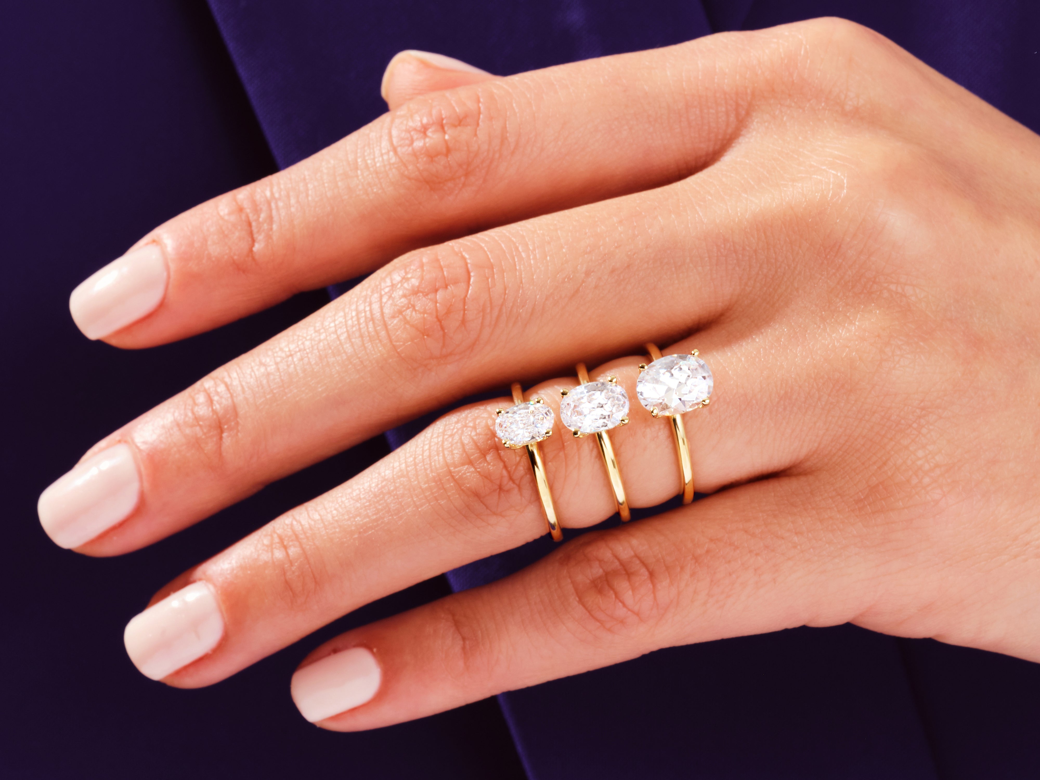 Three oval diamond engagement rings on a hand
