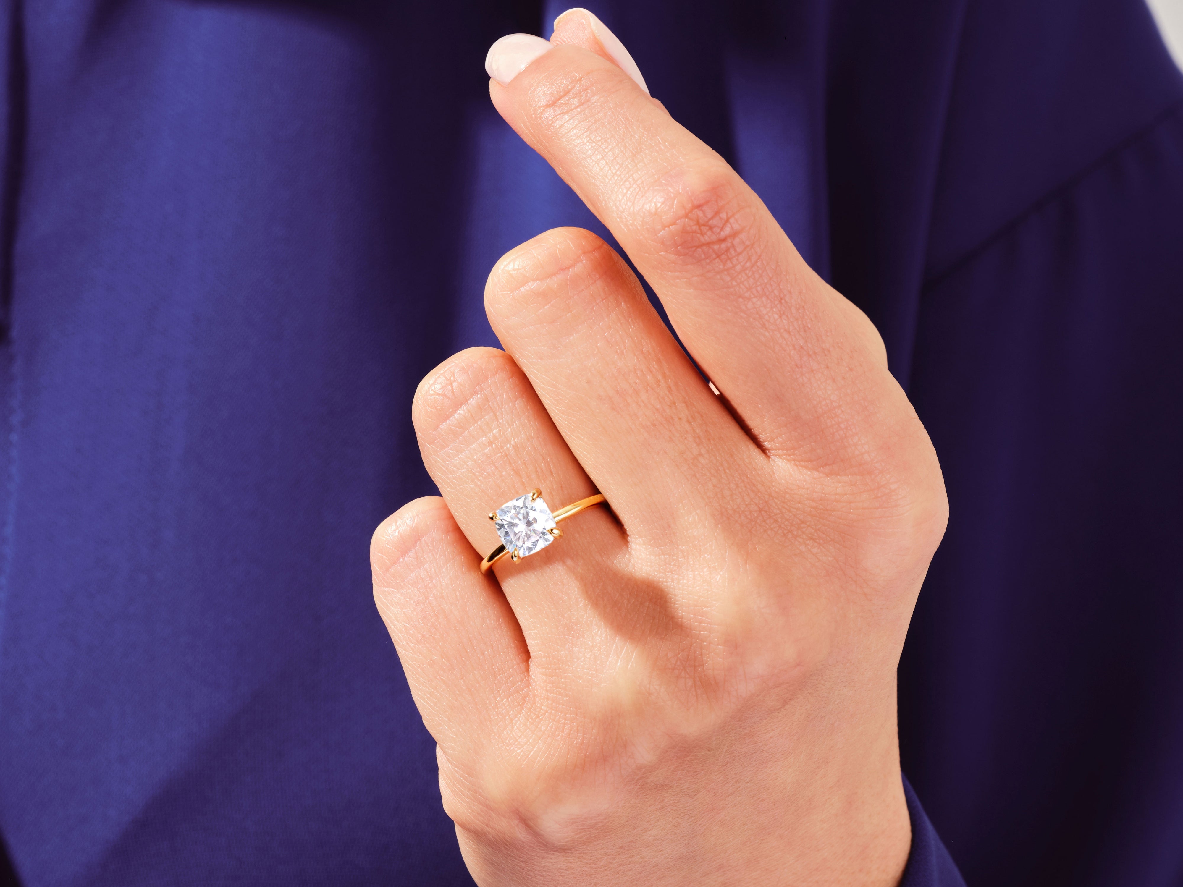 Gold ring with cushion-cut diamond on hand