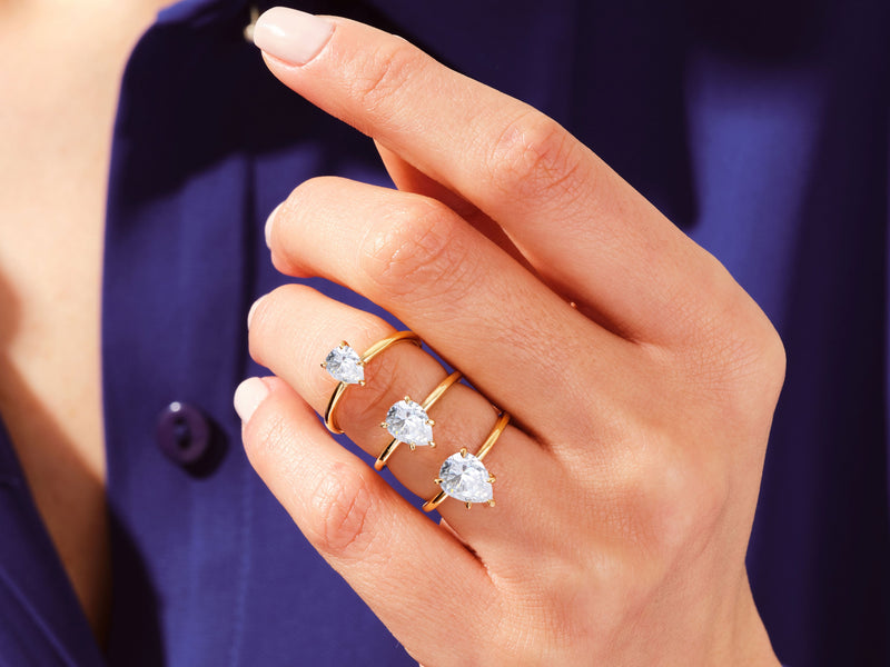 Gold rings with pear-shaped diamonds on a hand