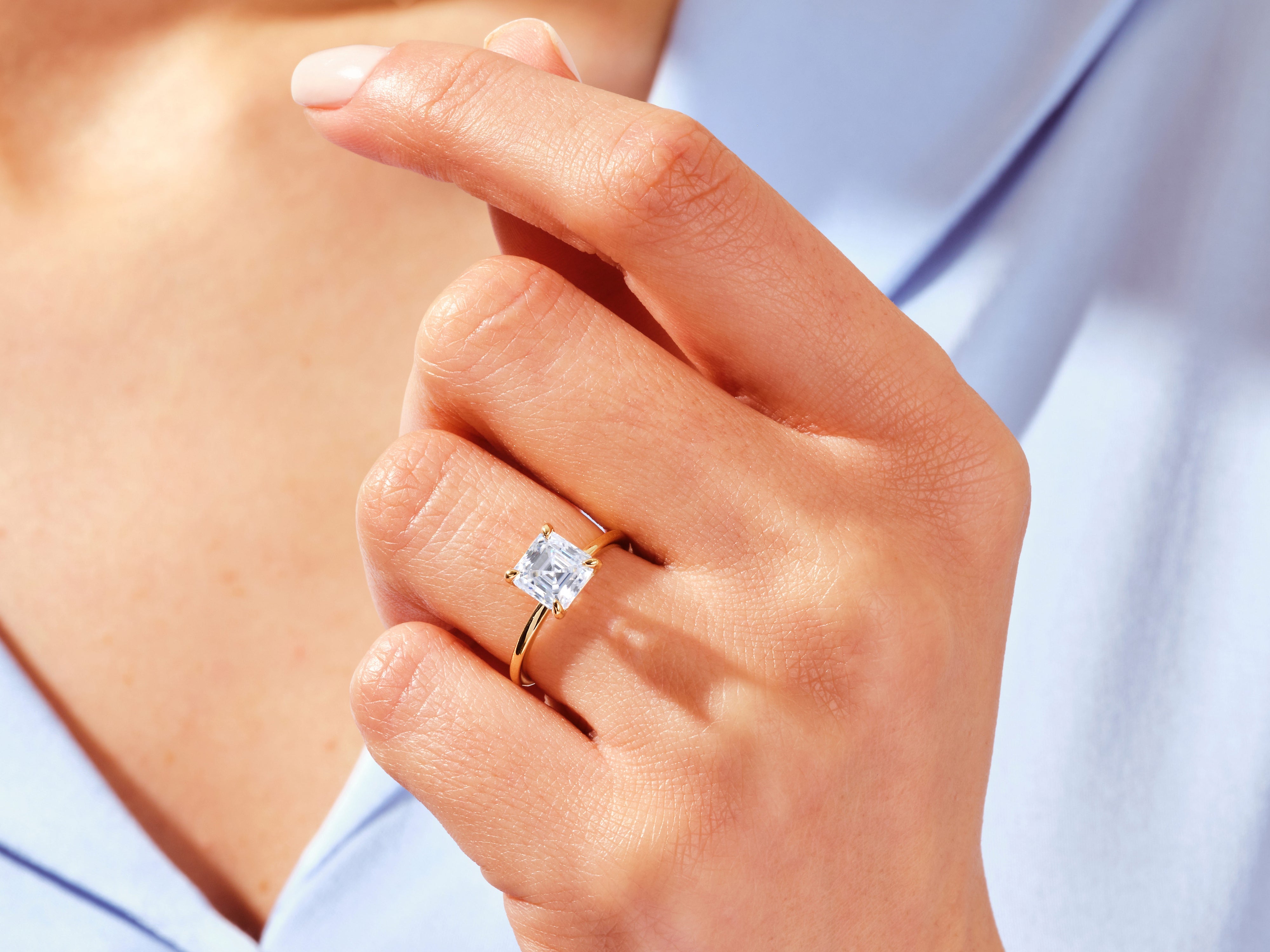 Gold ring with princess cut diamond on a woman's finger