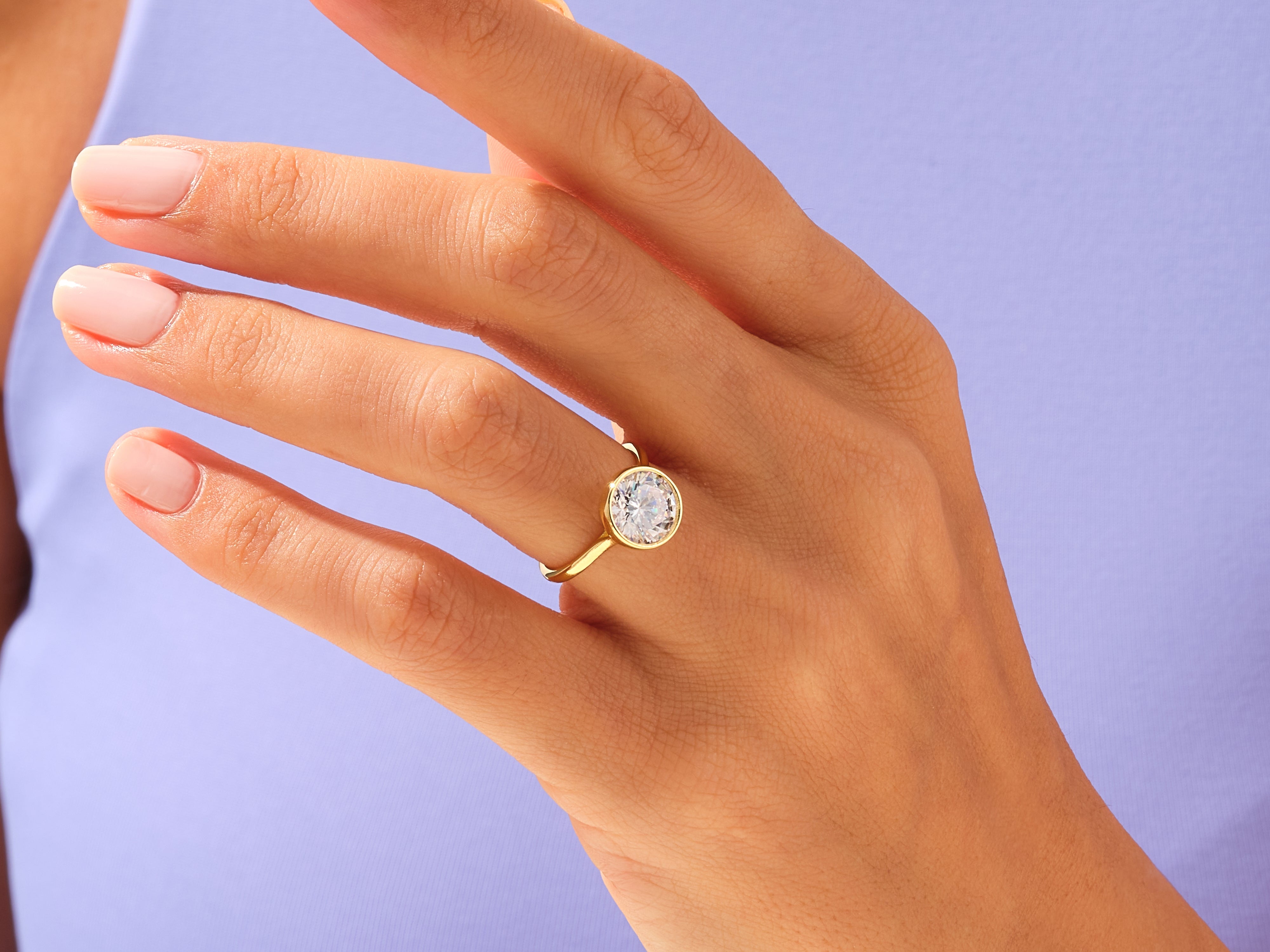 Gold bezel set diamond ring on a woman's hand