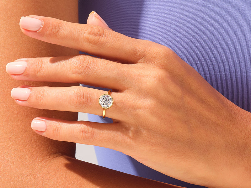 Gold bezel set diamond ring on a woman's hand
