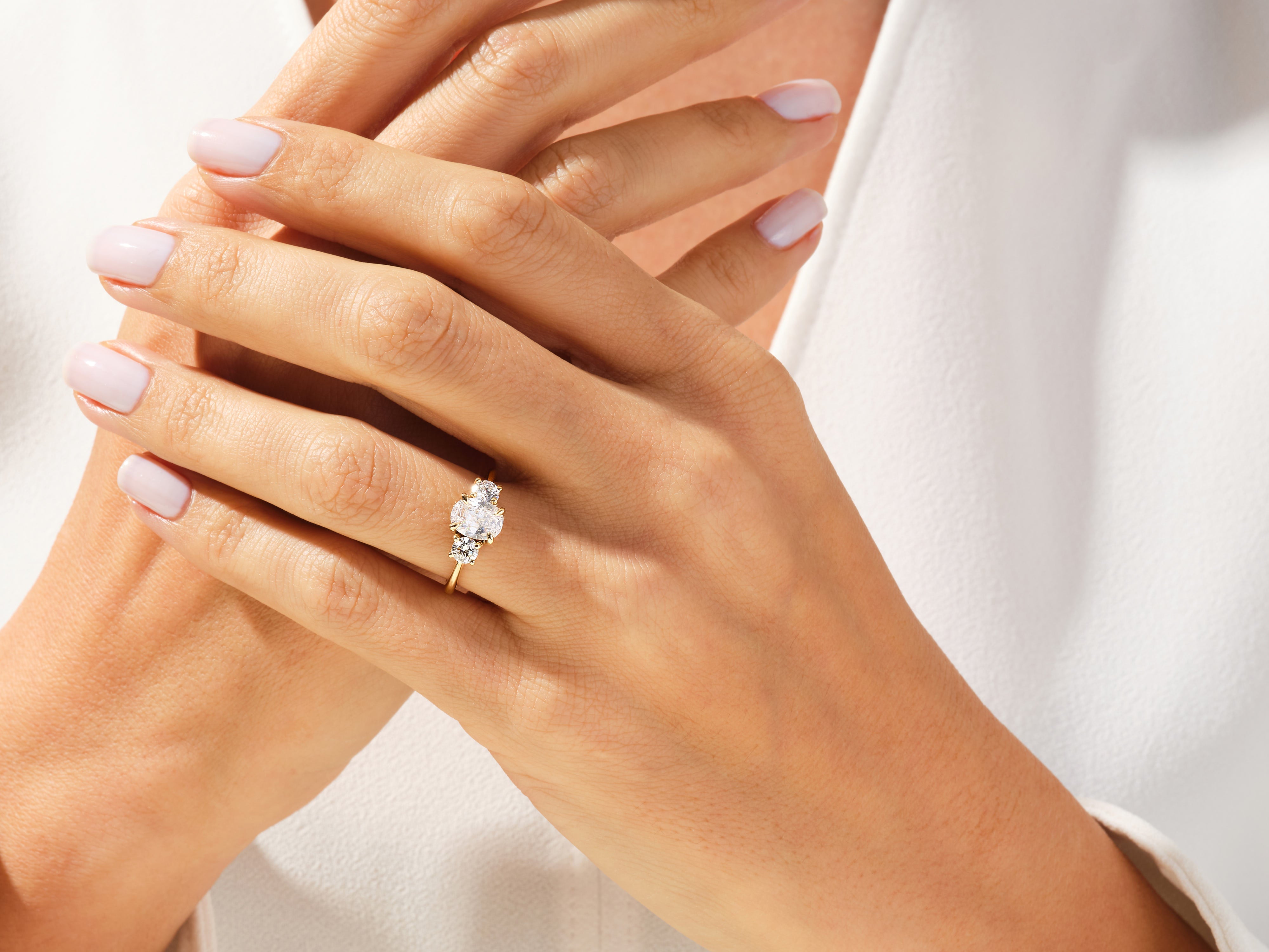 Gold three-stone diamond engagement ring on a woman's hand