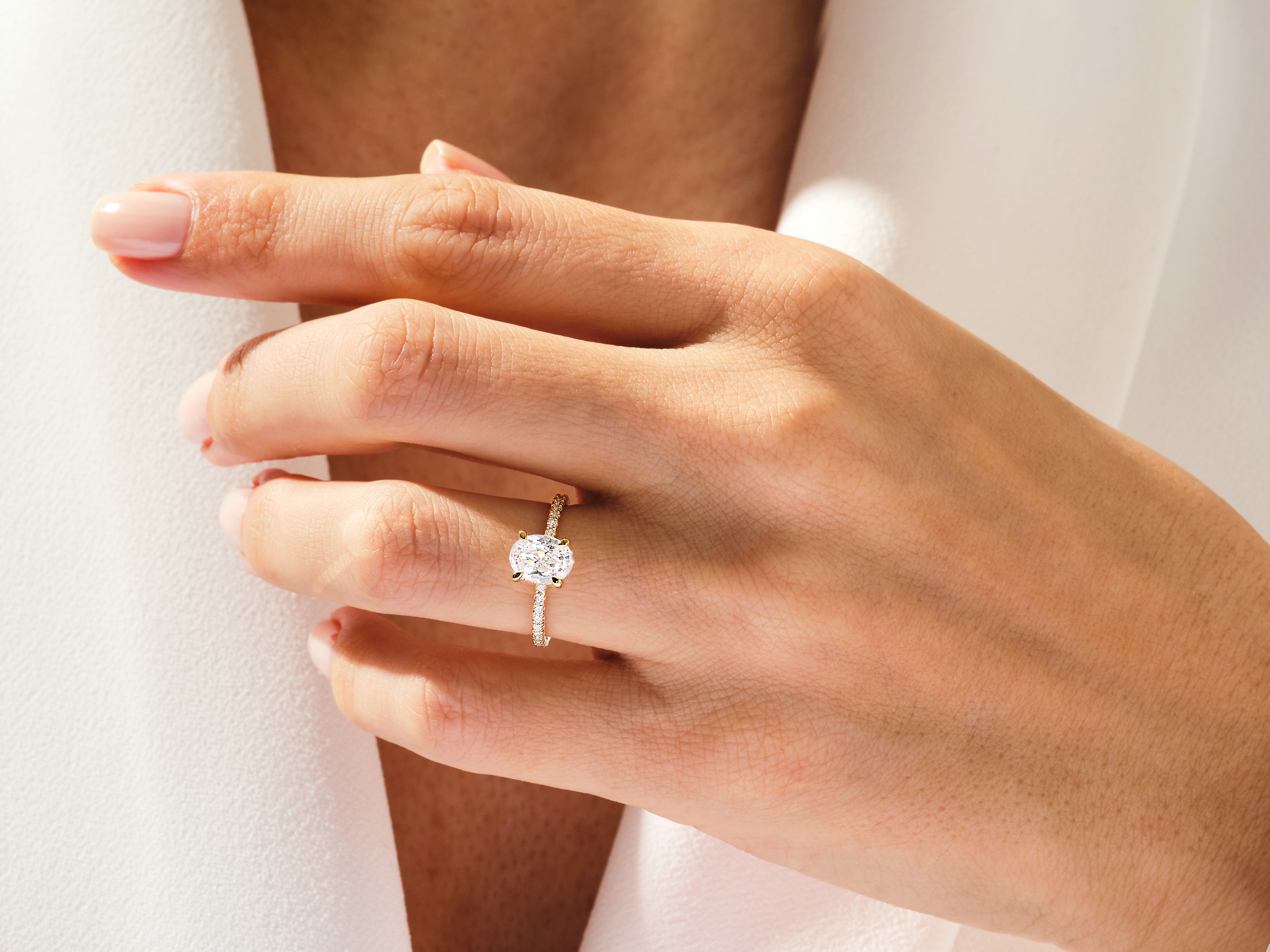 Oval diamond engagement ring with pave band on hand