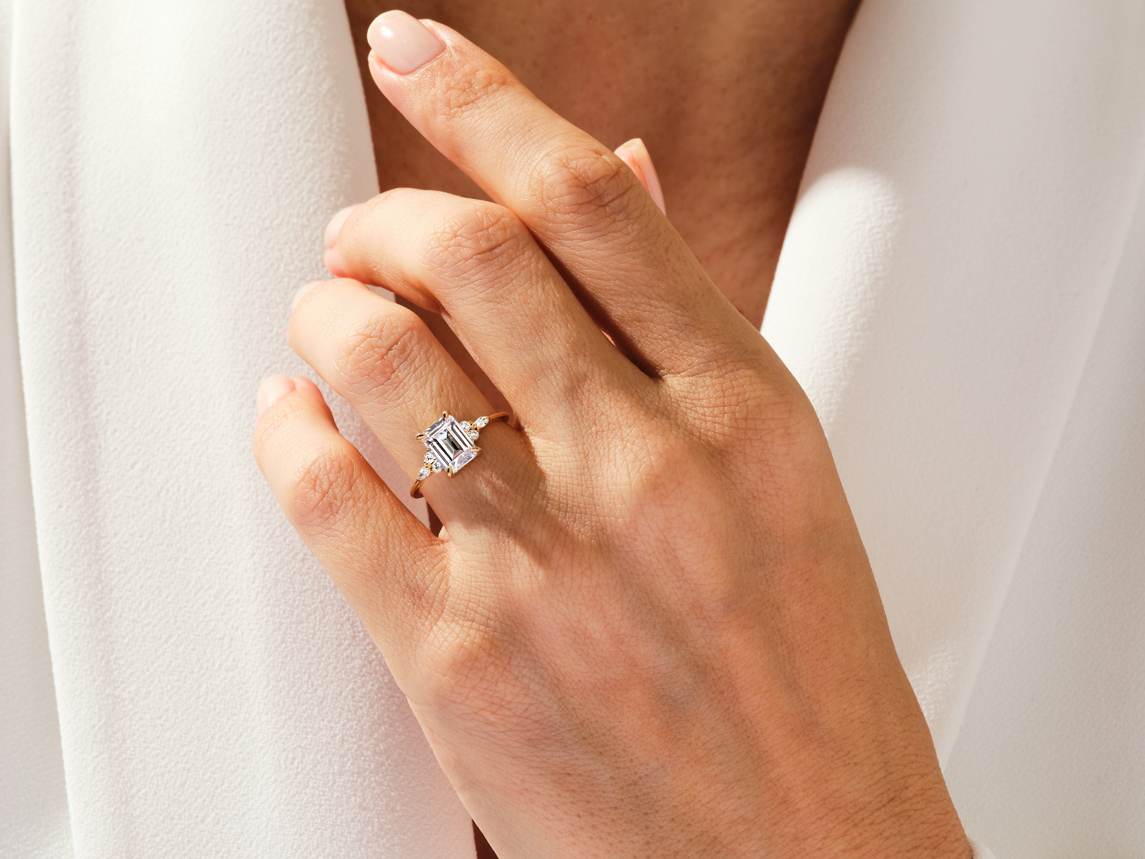 Emerald cut diamond ring with side stones on a hand