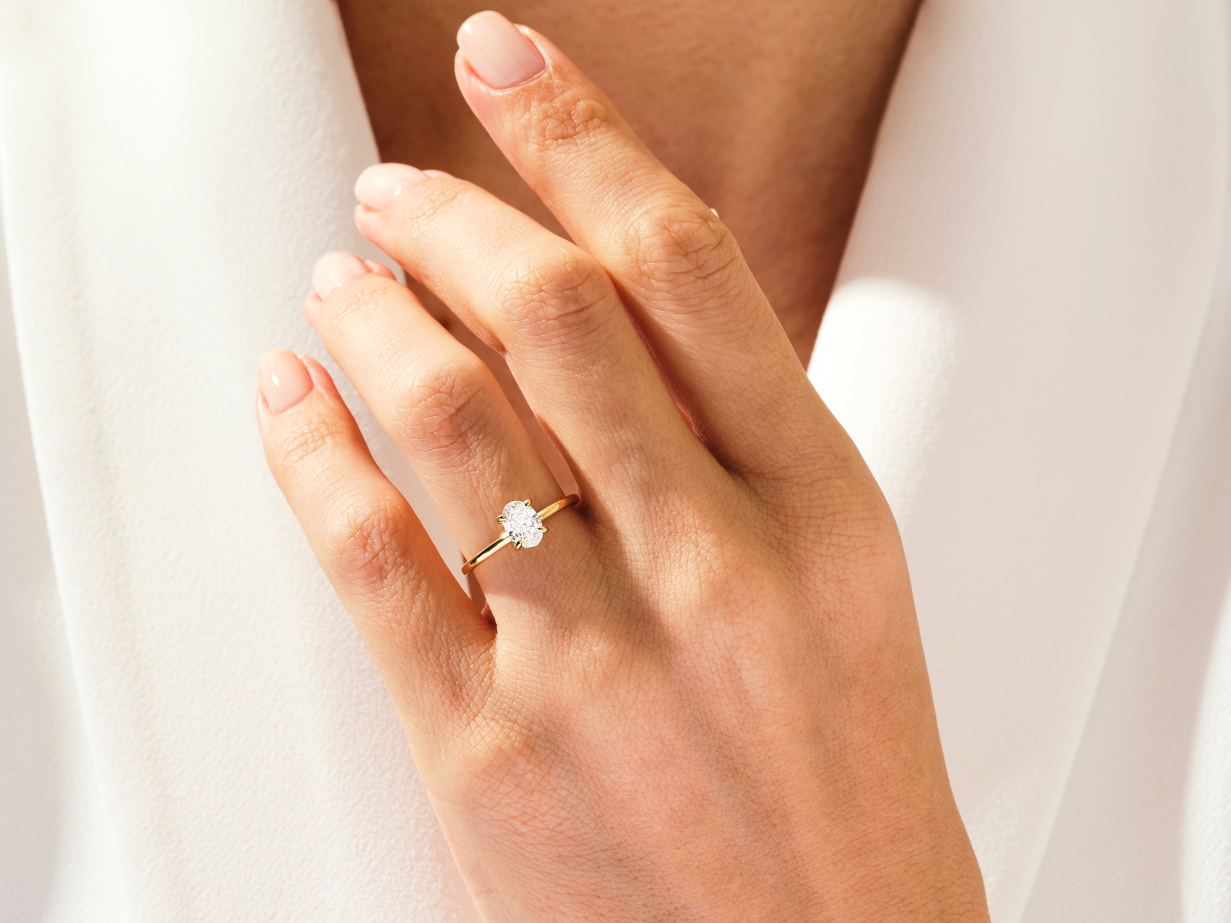 Gold oval diamond engagement ring on a woman's finger