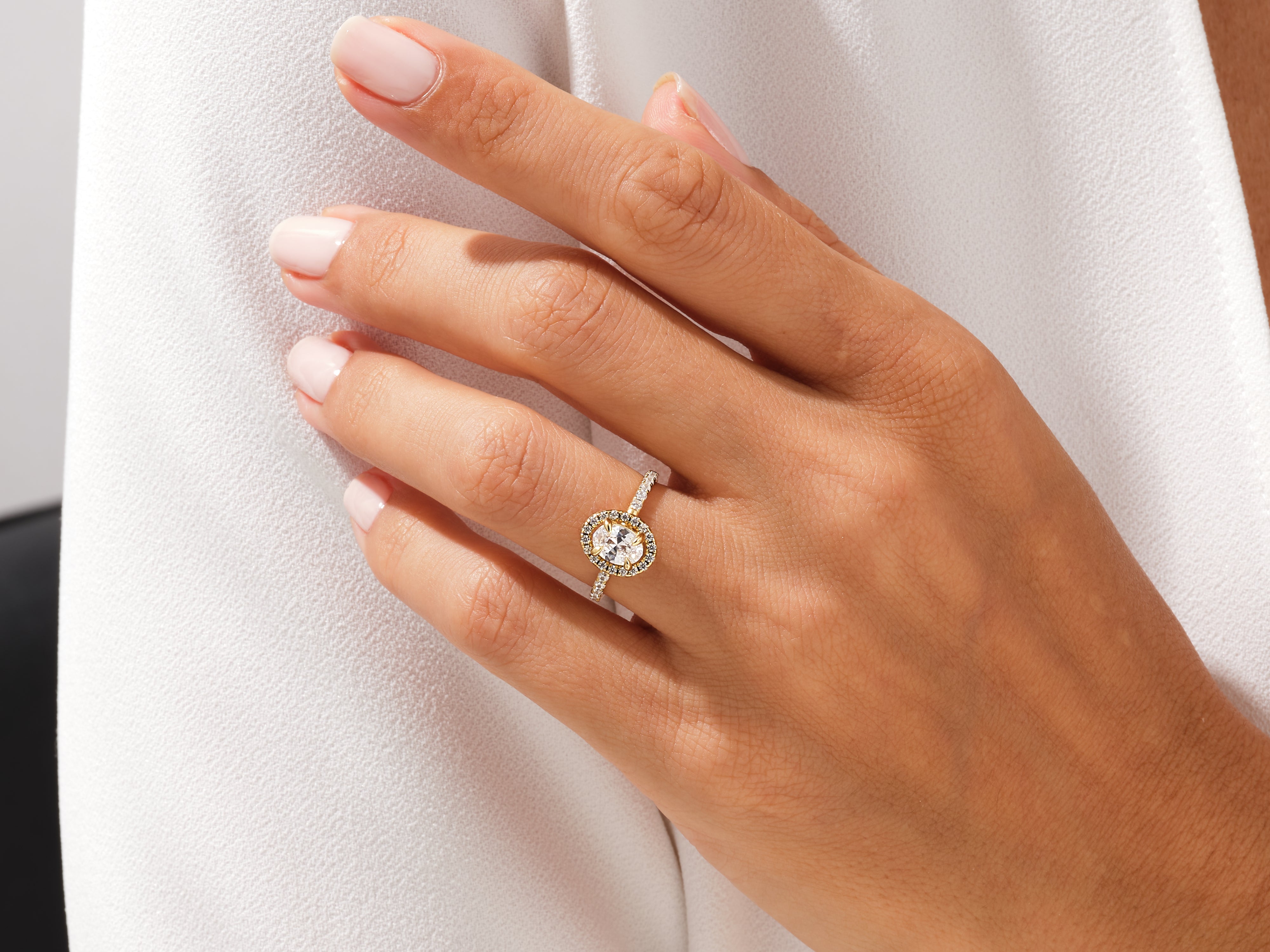 Oval diamond halo engagement ring on a woman's hand