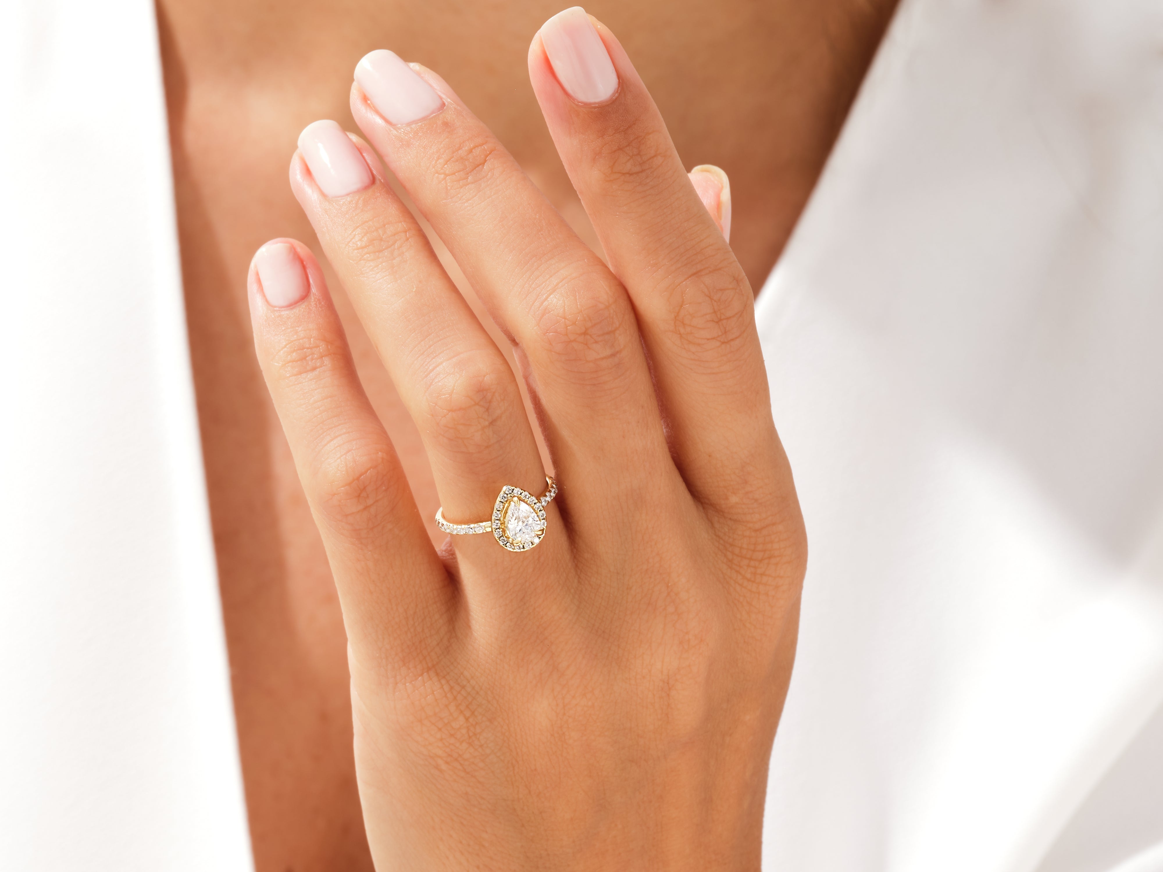 Gold pear-shaped diamond engagement ring on a woman's hand