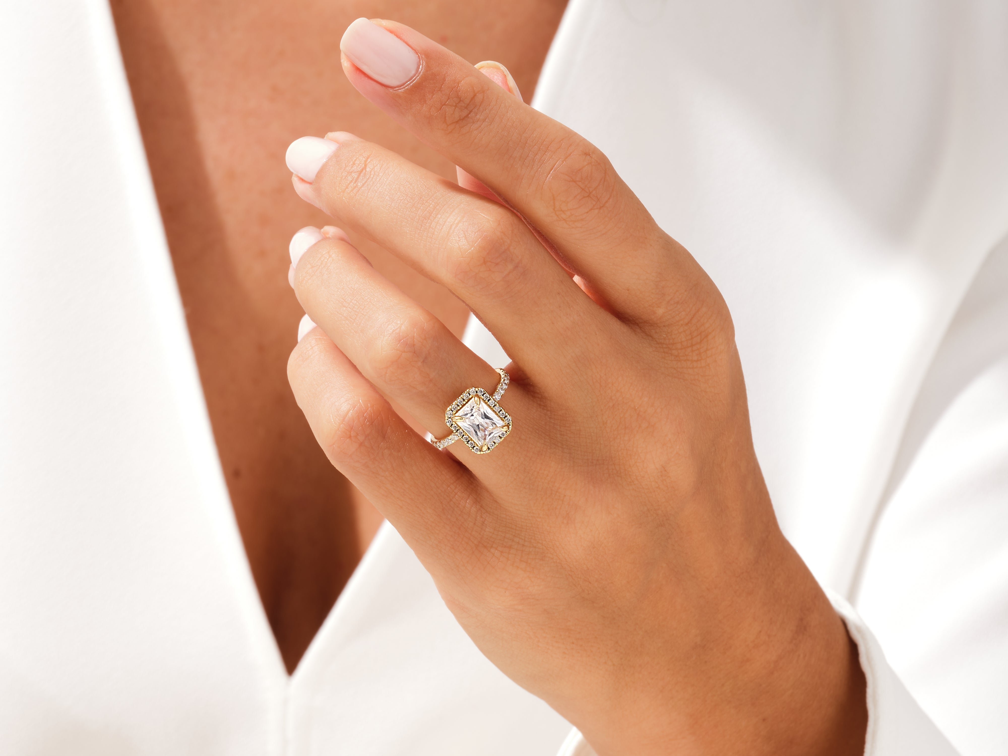 Emerald cut diamond halo ring on a woman's hand