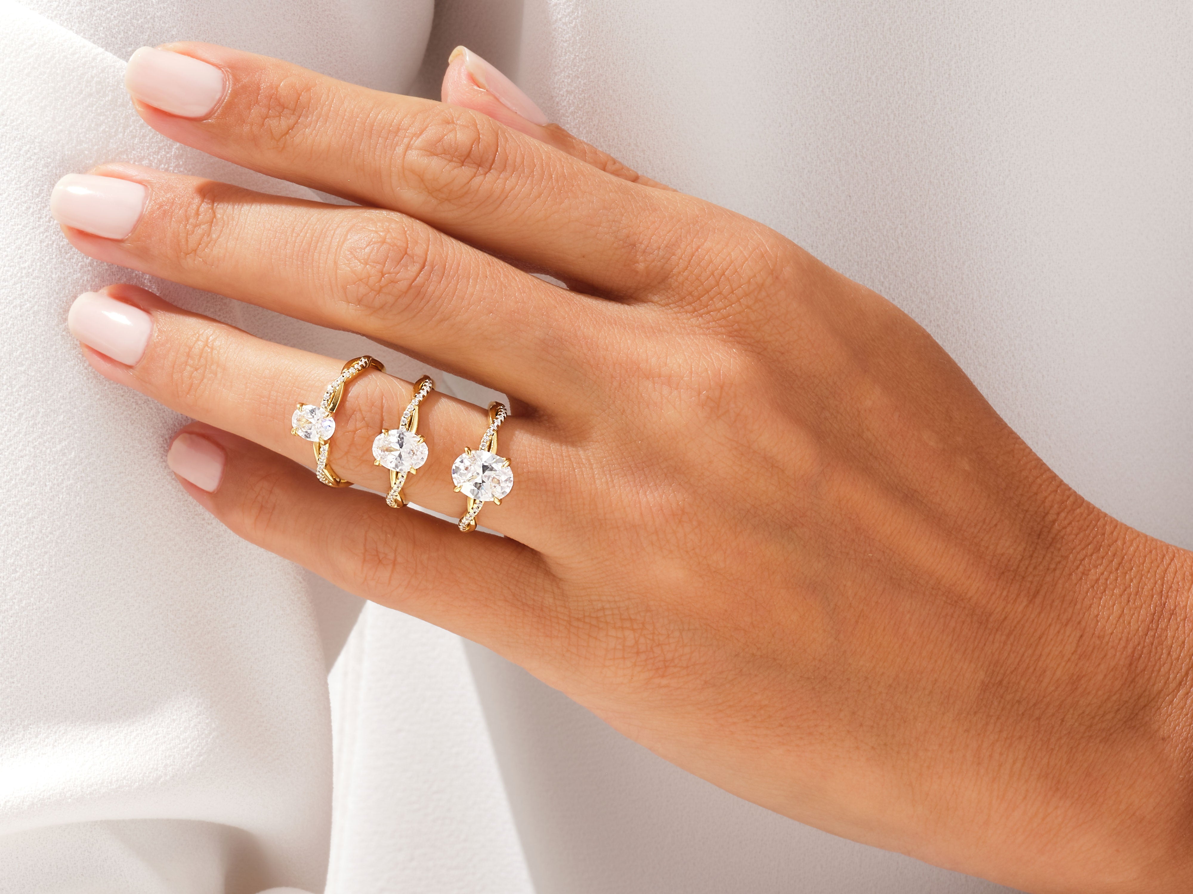 Three oval diamond engagement rings on a hand
