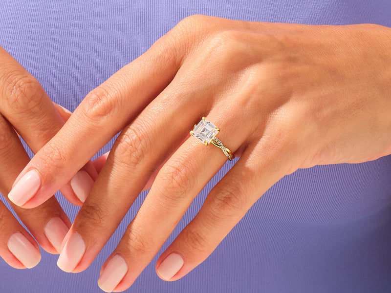Gold engagement ring with princess cut diamond on hand