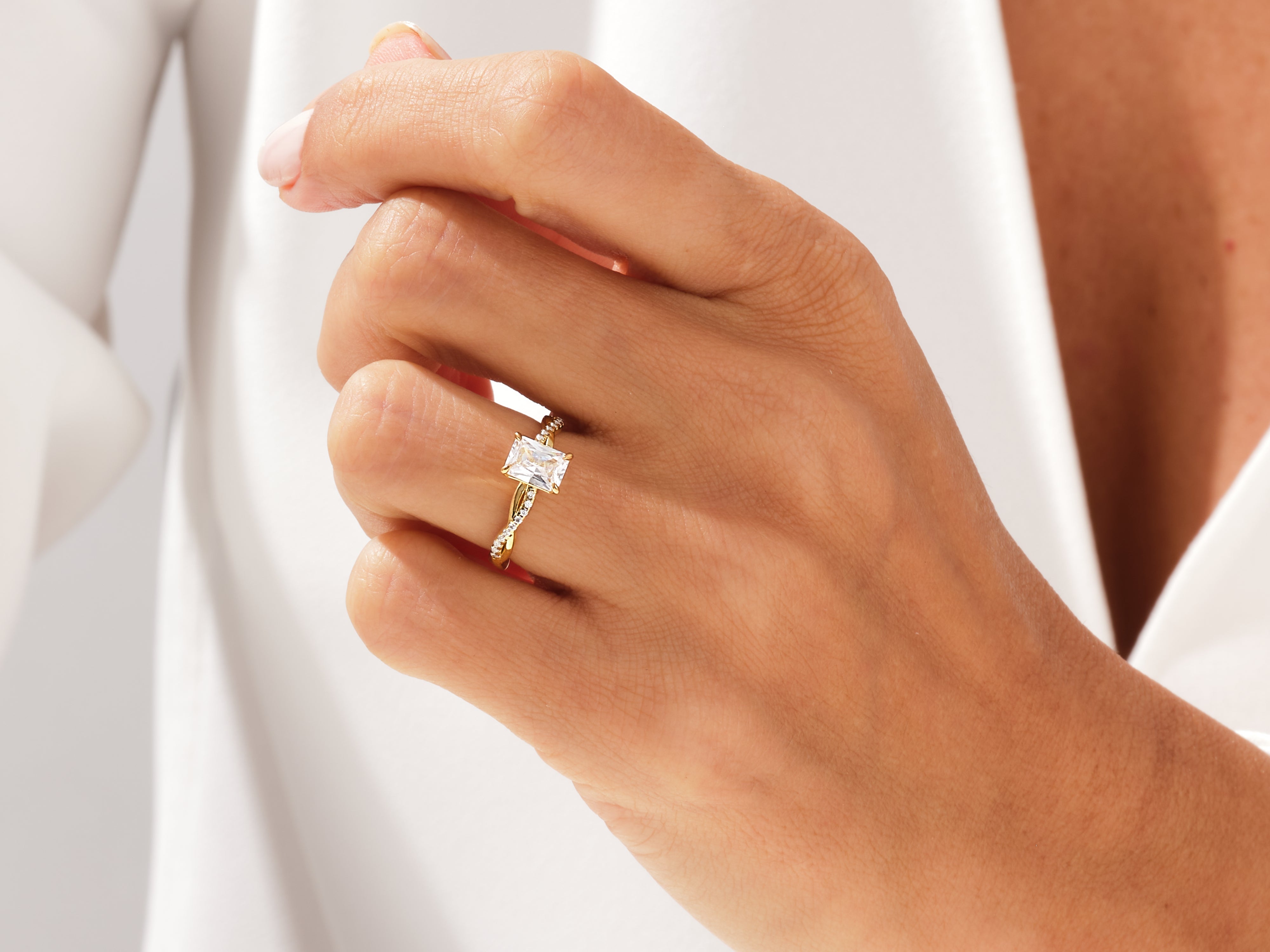 Gold ring with emerald cut diamond and twisted band on hand