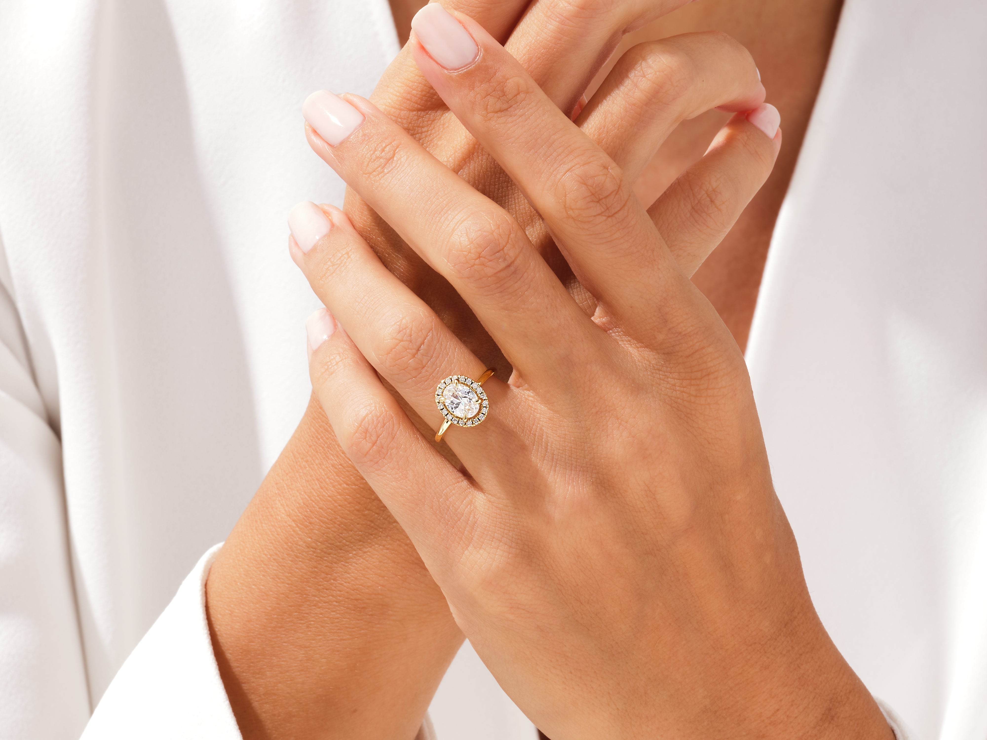 Gold oval halo engagement ring on a woman's hand