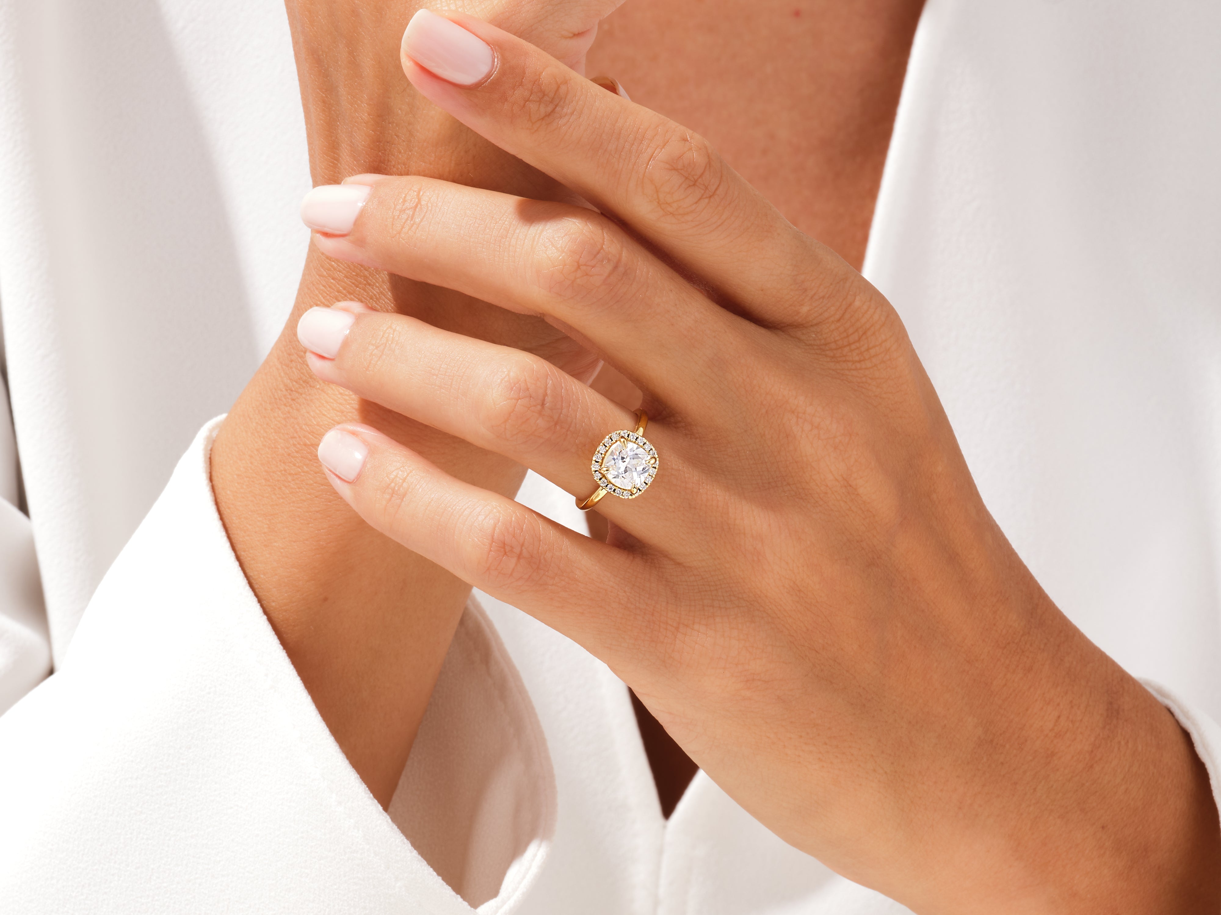 Gold halo engagement ring with diamond center stone on a woman's hand