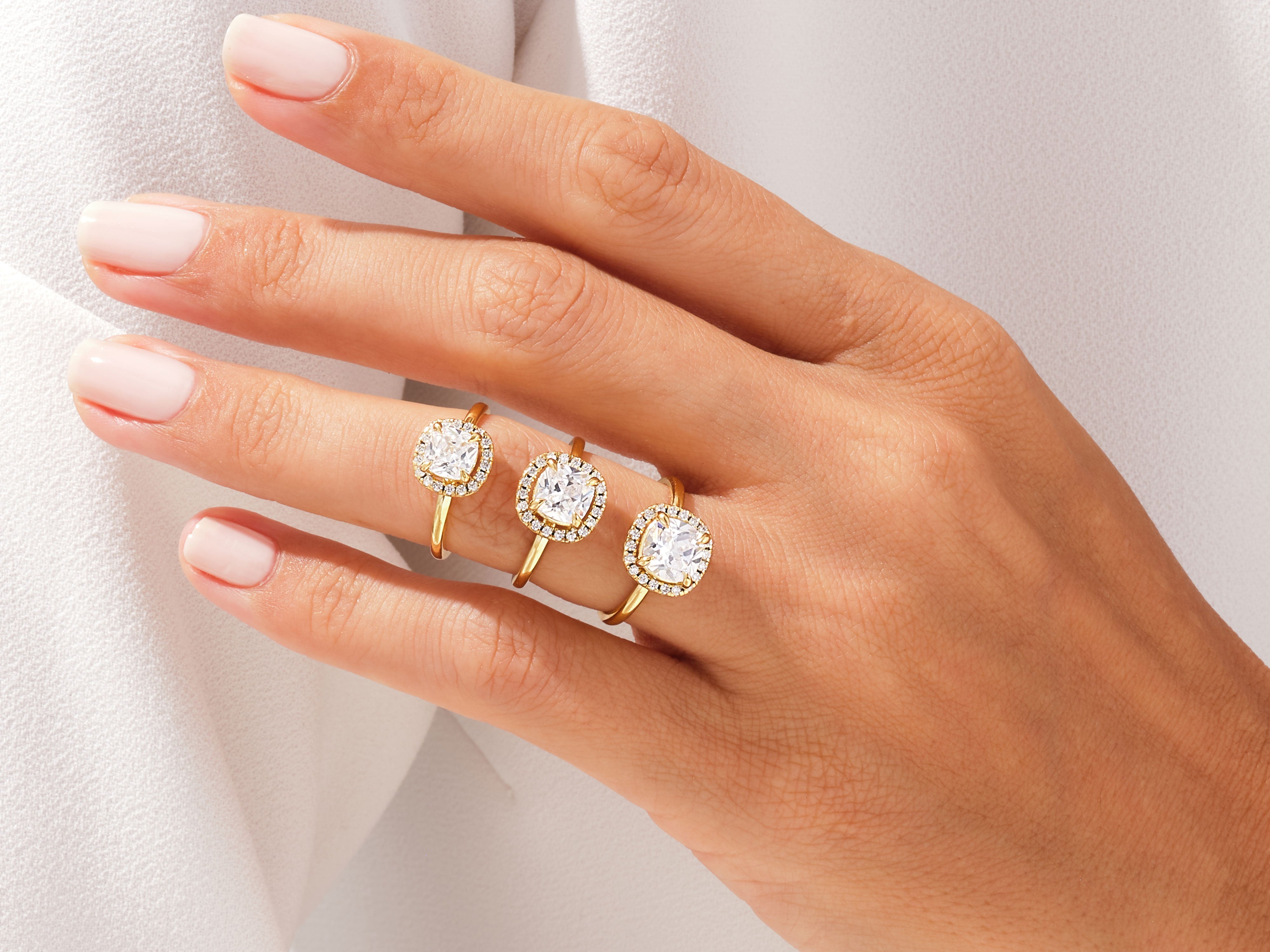 Three gold diamond halo rings on a hand