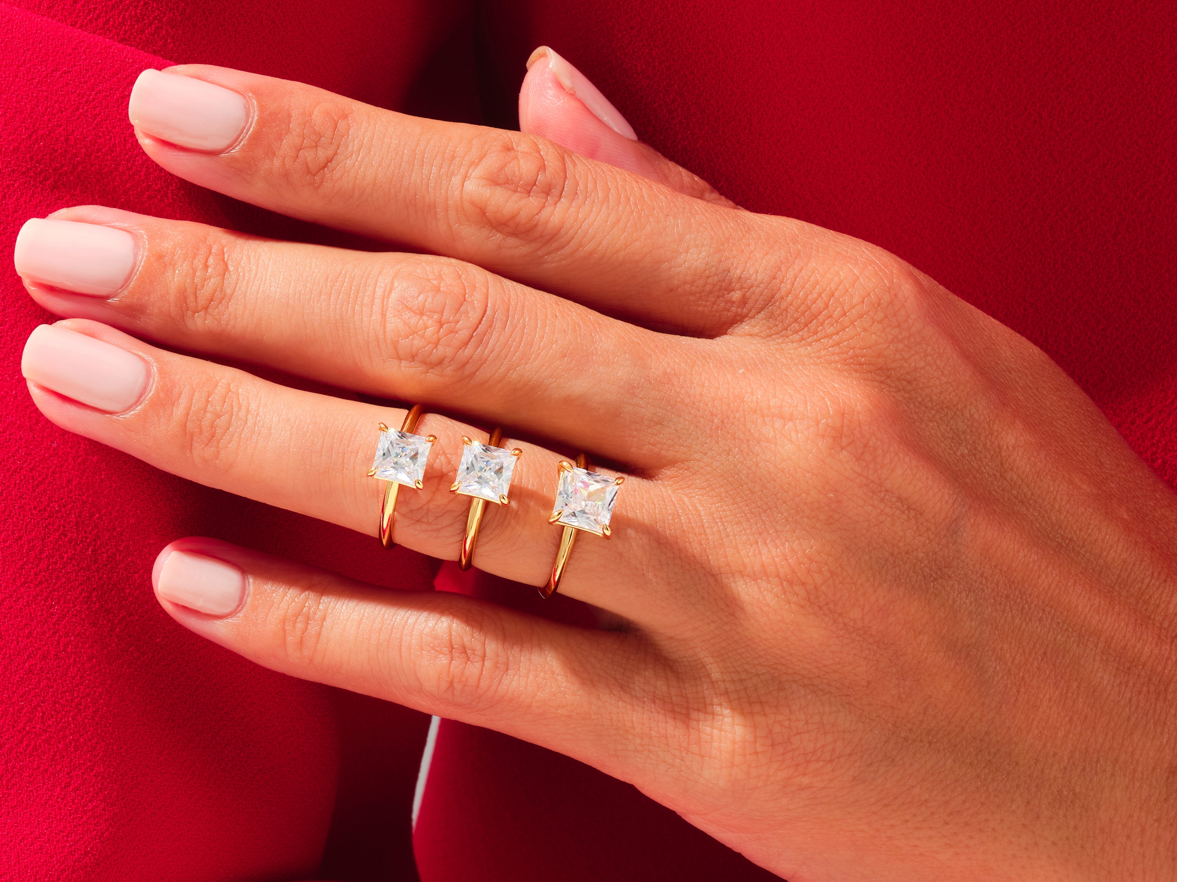 Gold rings with princess cut diamonds on a hand