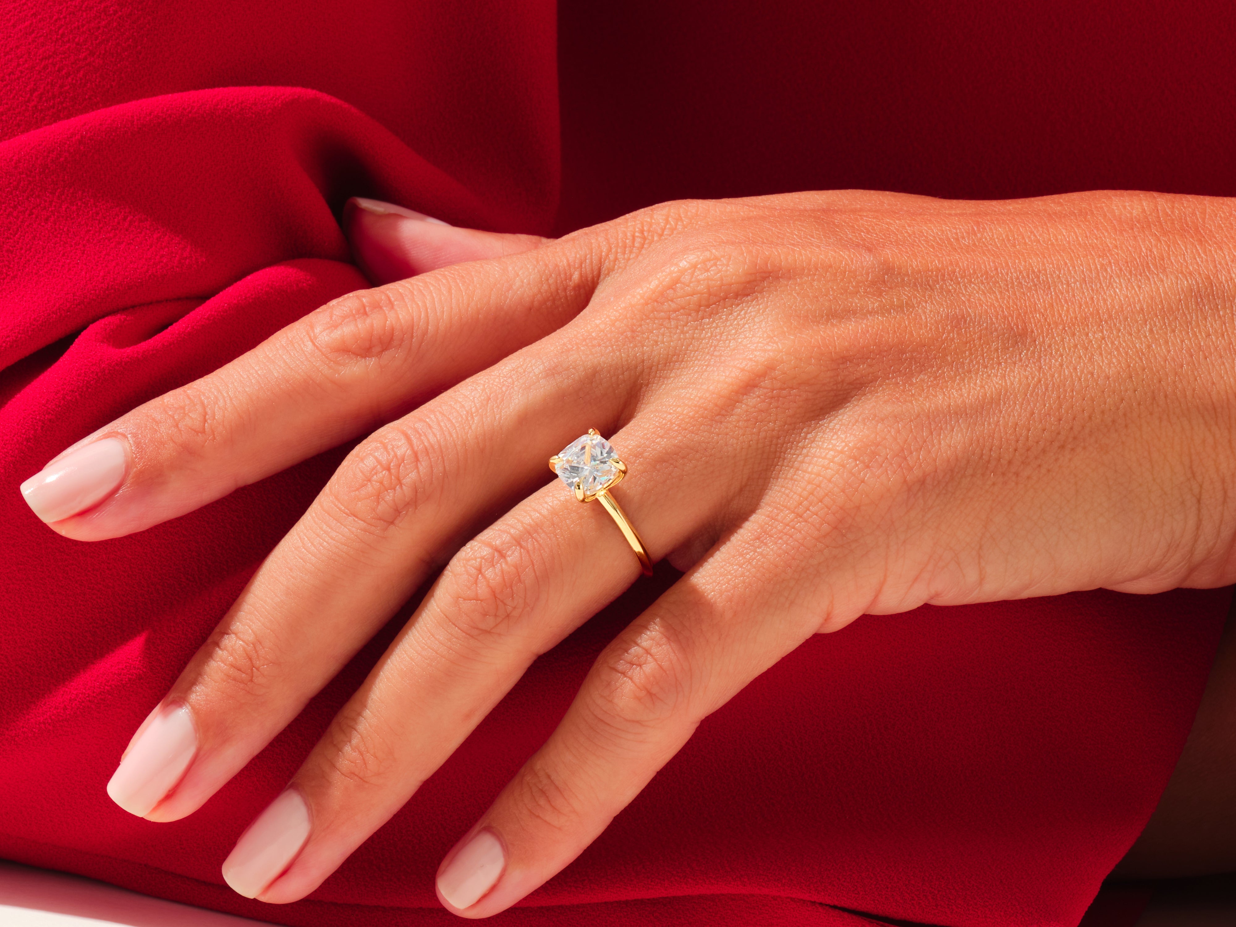 Diamond engagement ring on hand, luxury jewelry, red silk background