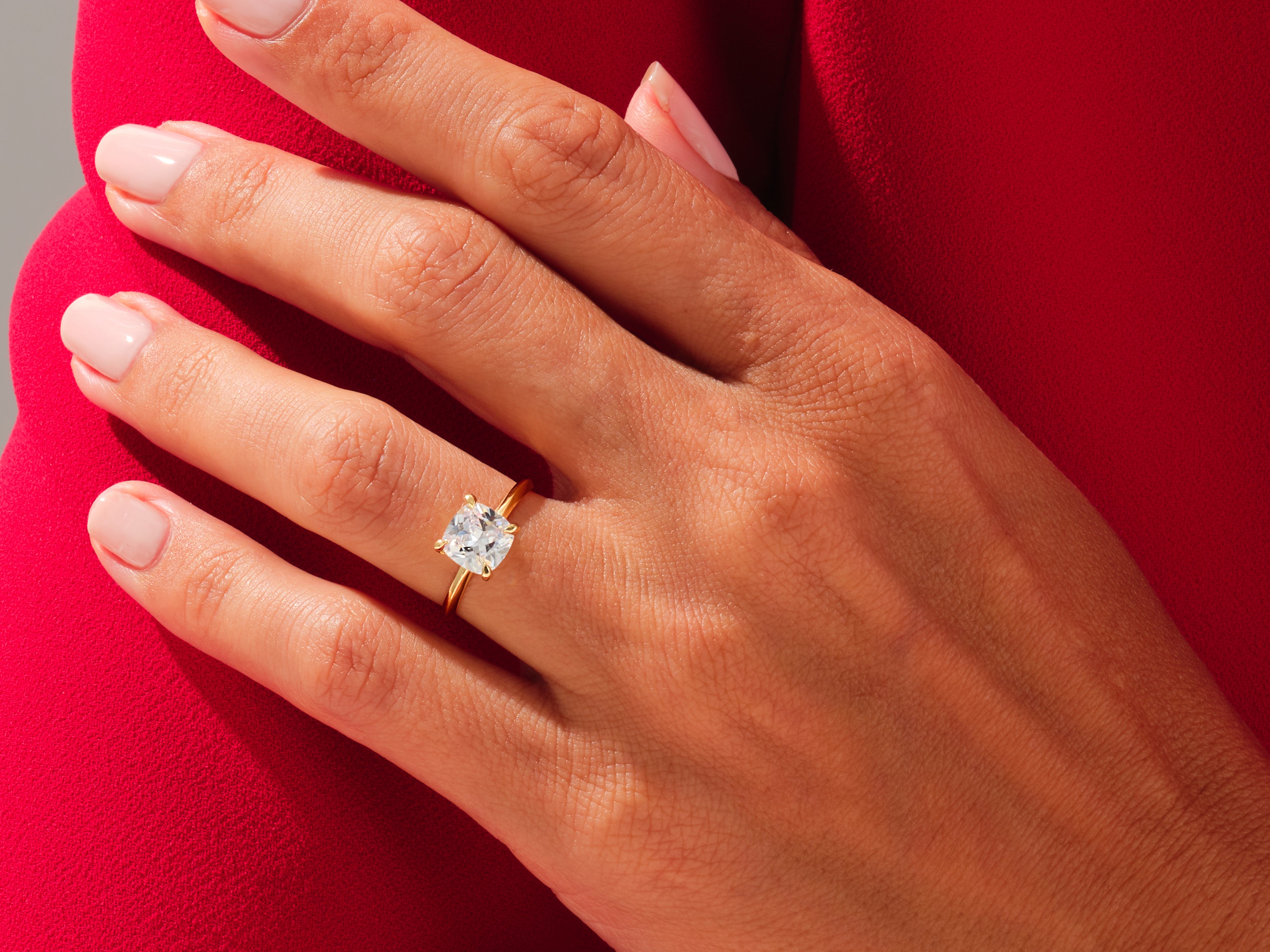 Gold ring with cushion cut diamond on hand