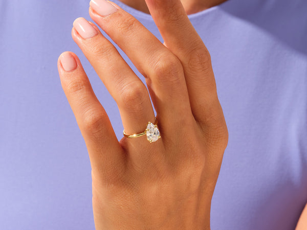 Gold pear cut diamond engagement ring on a woman's hand