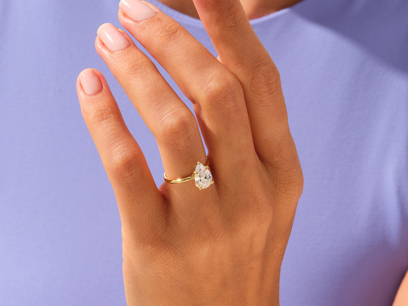 Gold pear cut diamond engagement ring on a woman's hand