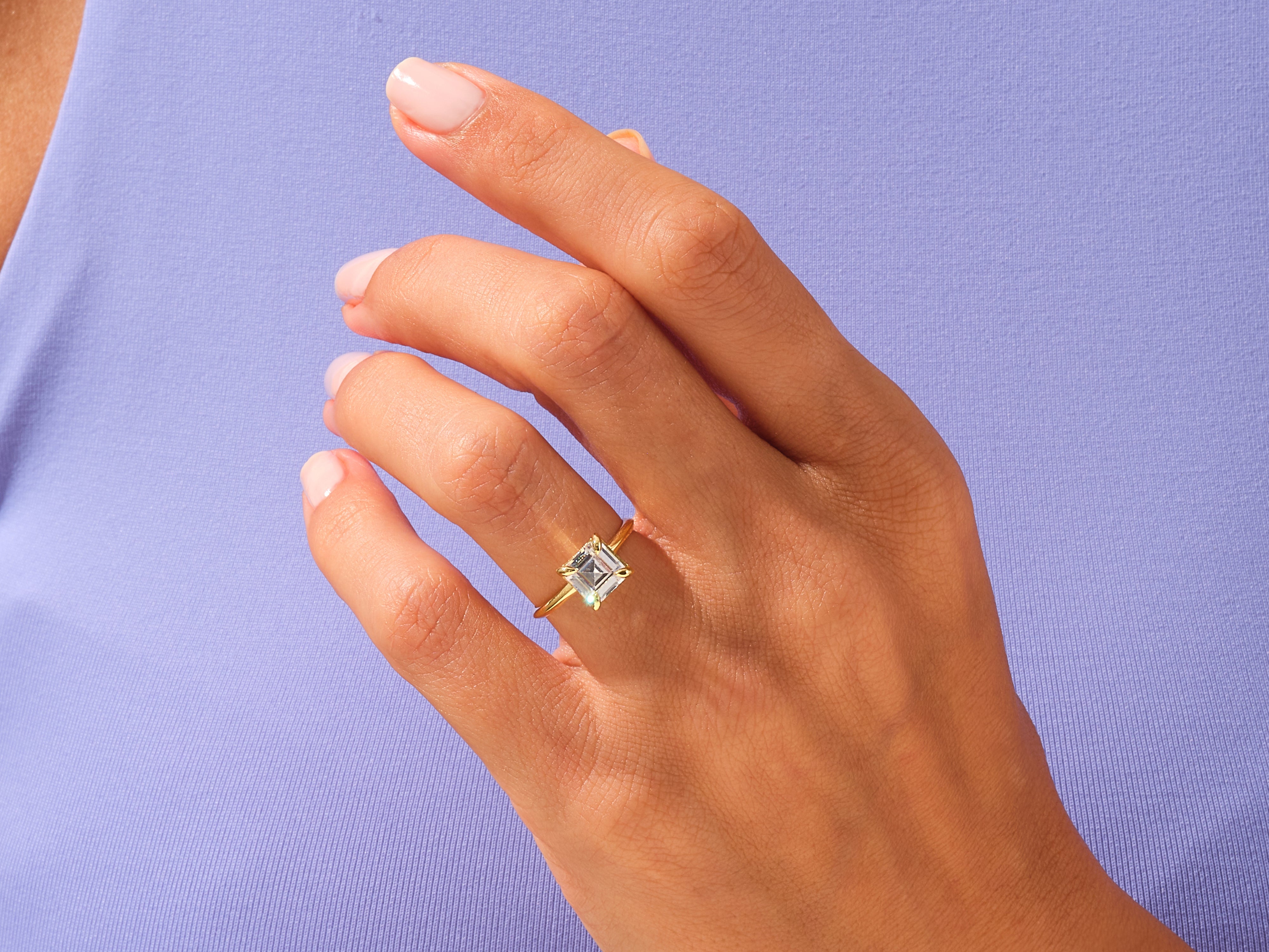 Gold ring with emerald cut diamond on a woman's hand