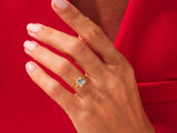 Gold ring with square diamond on hand, red background