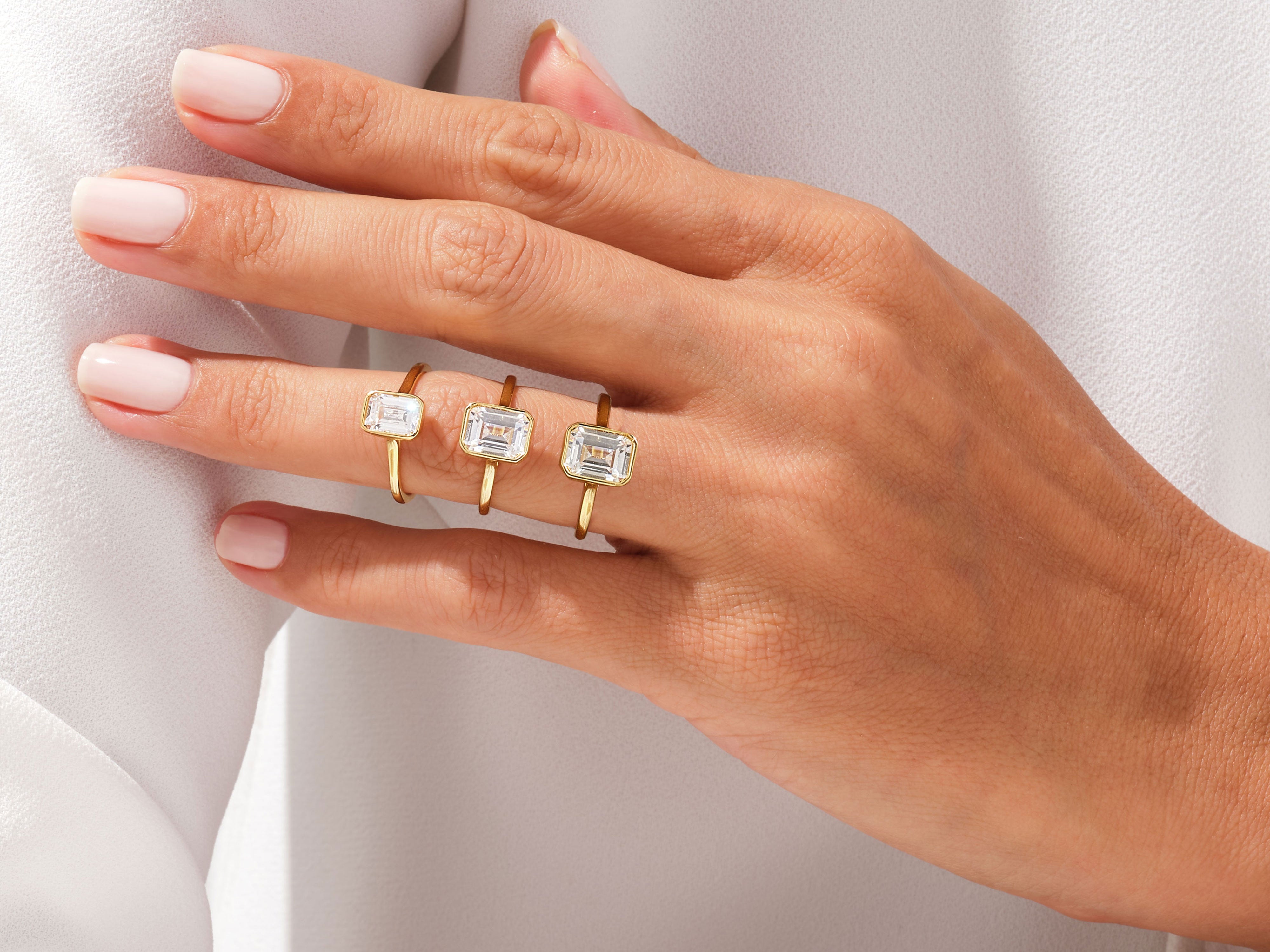 Three emerald cut diamond rings on a hand