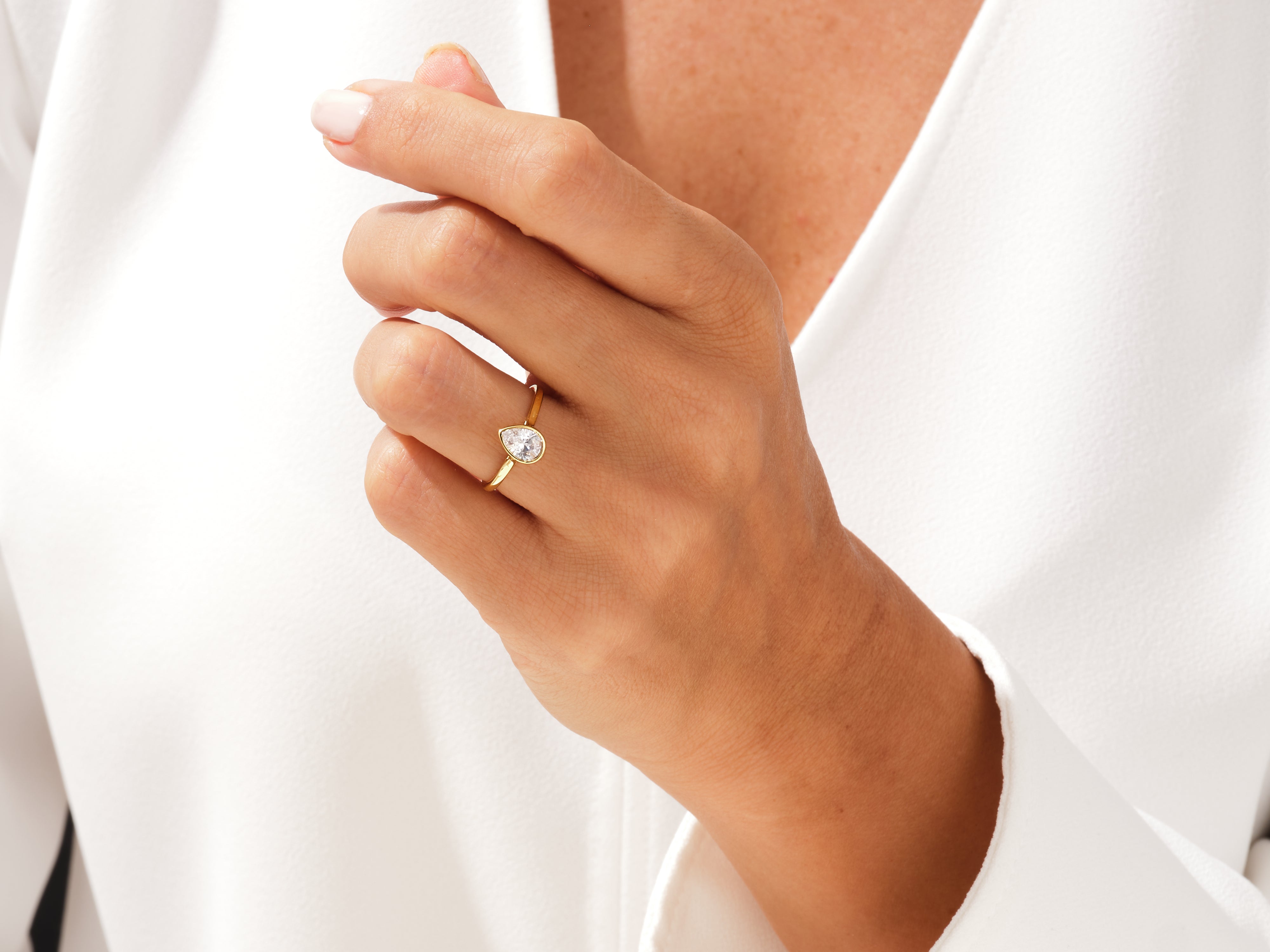 Gold pear-shaped diamond ring on a woman's hand