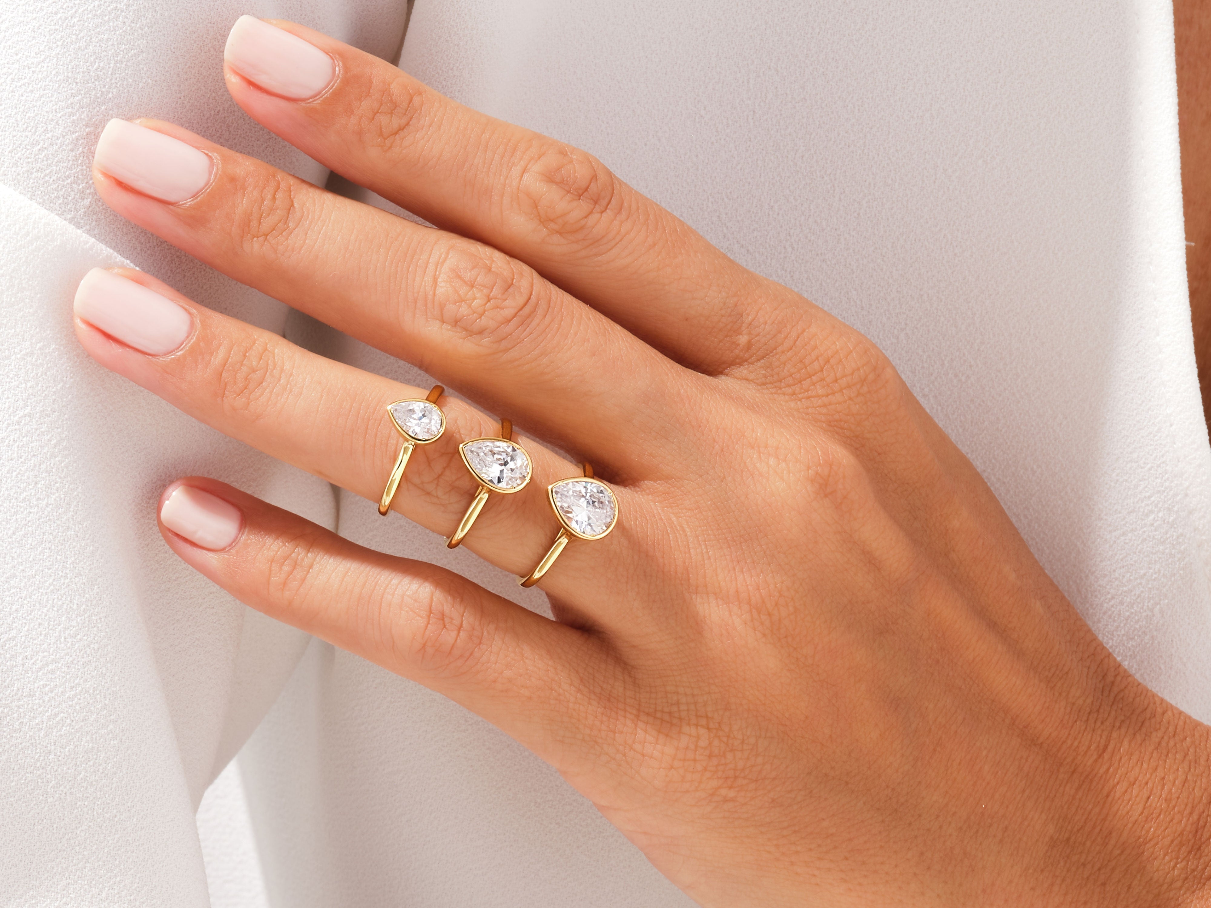 Gold pear-cut diamond rings on a woman's hand
