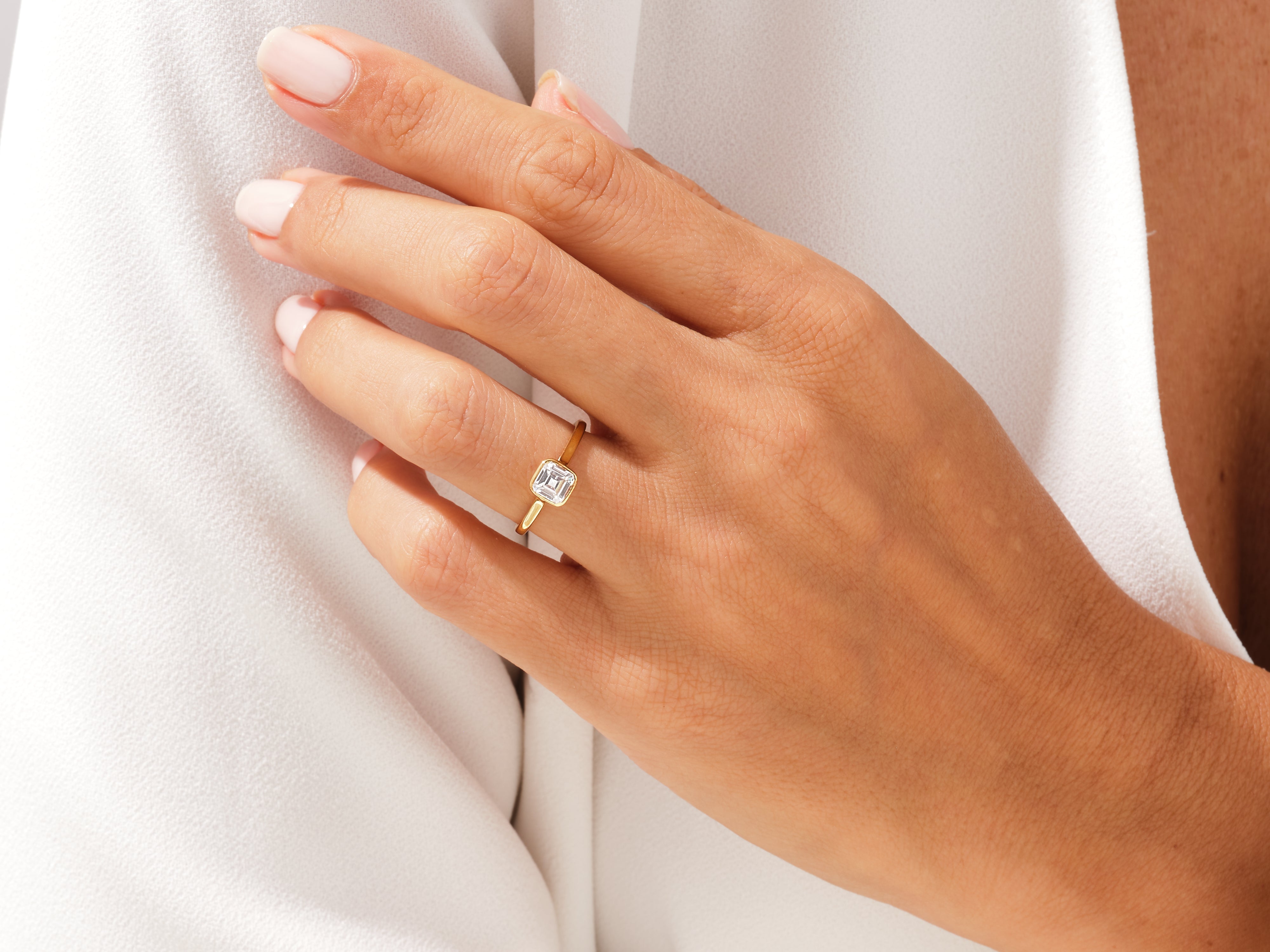 Gold ring with emerald-cut diamond on a woman's finger