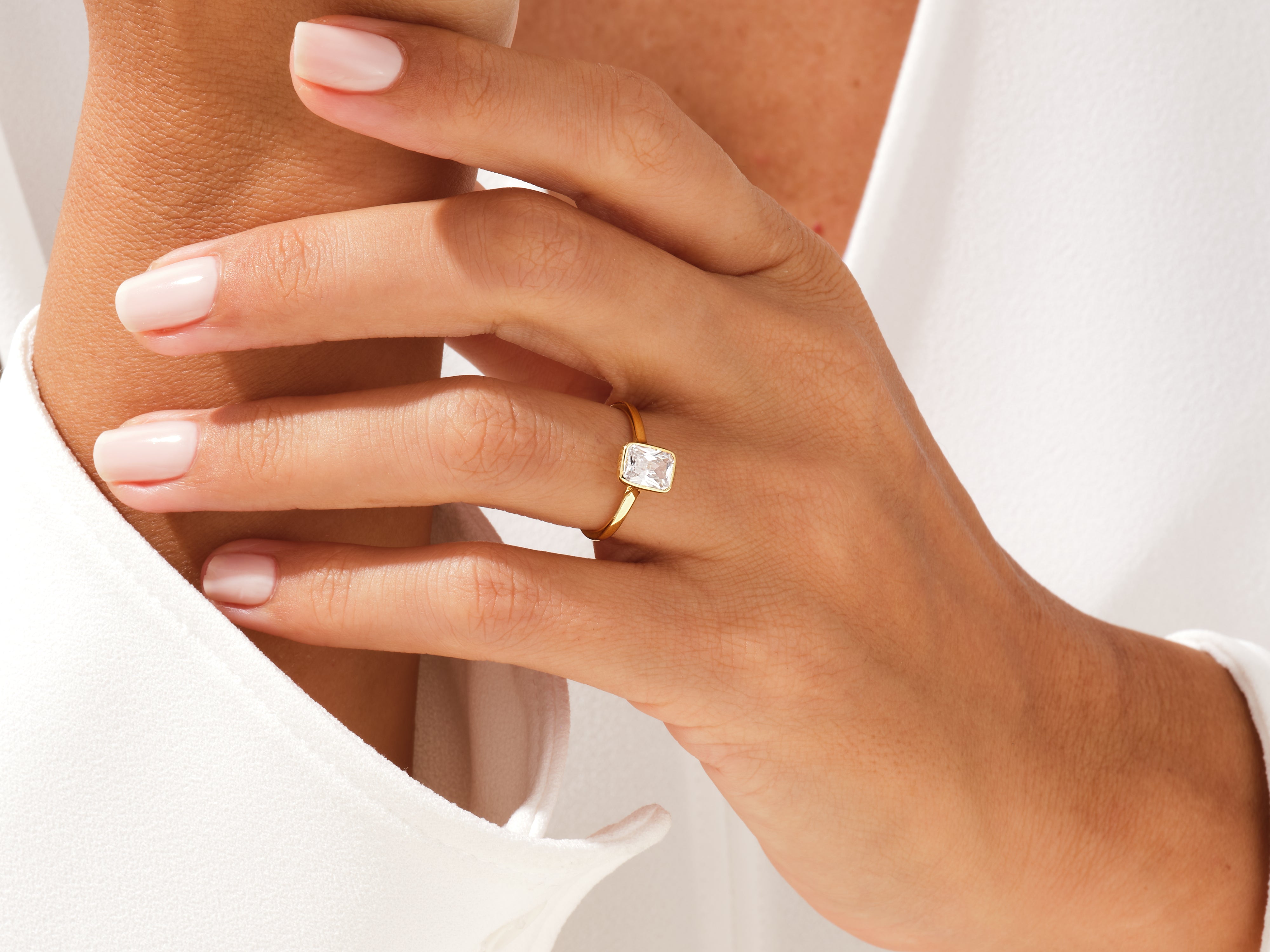 Gold ring with emerald-cut diamond on a woman's hand