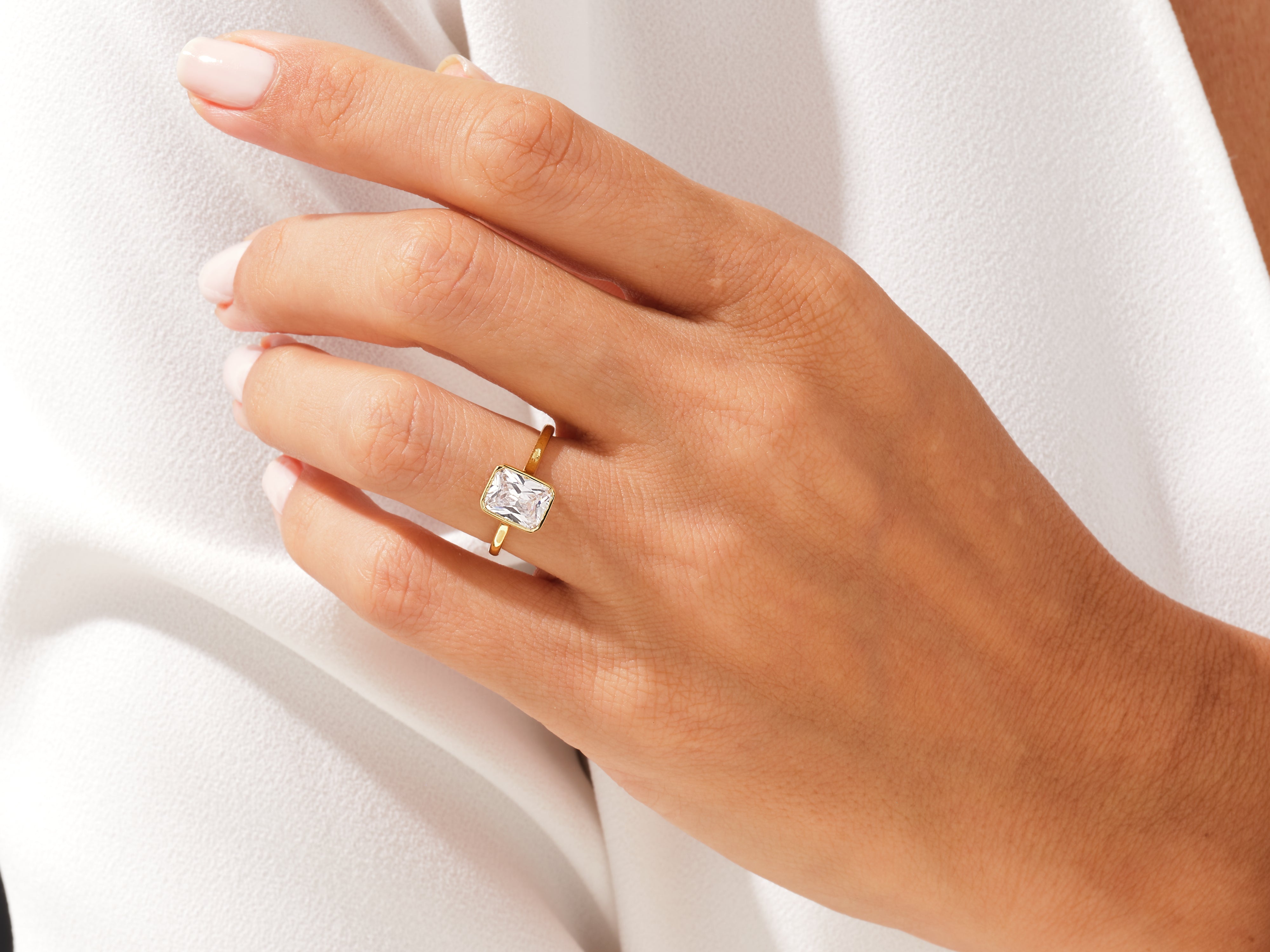 Gold ring with emerald cut diamond on hand