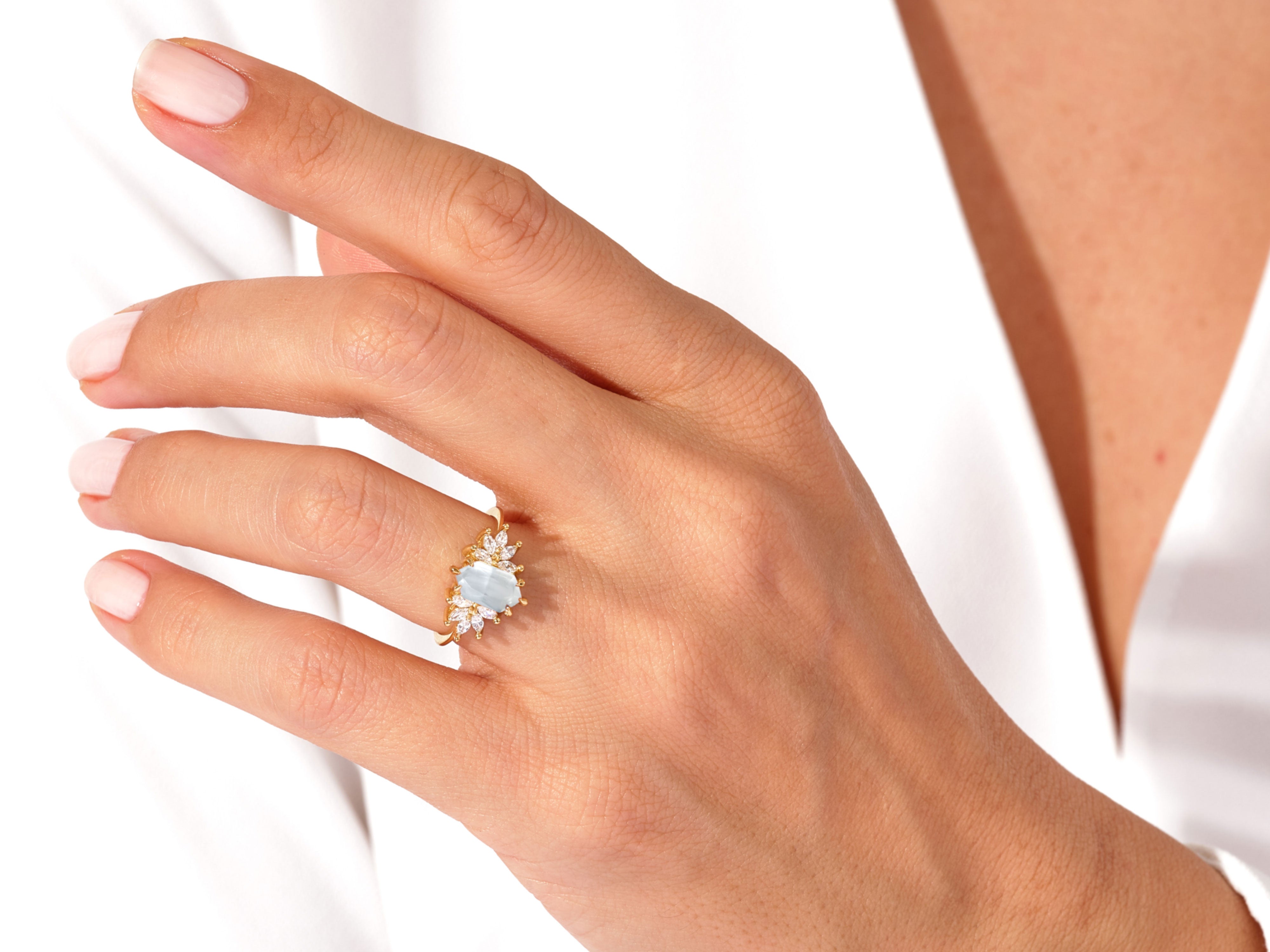 Gold ring with aquamarine and diamond accents on a woman's hand