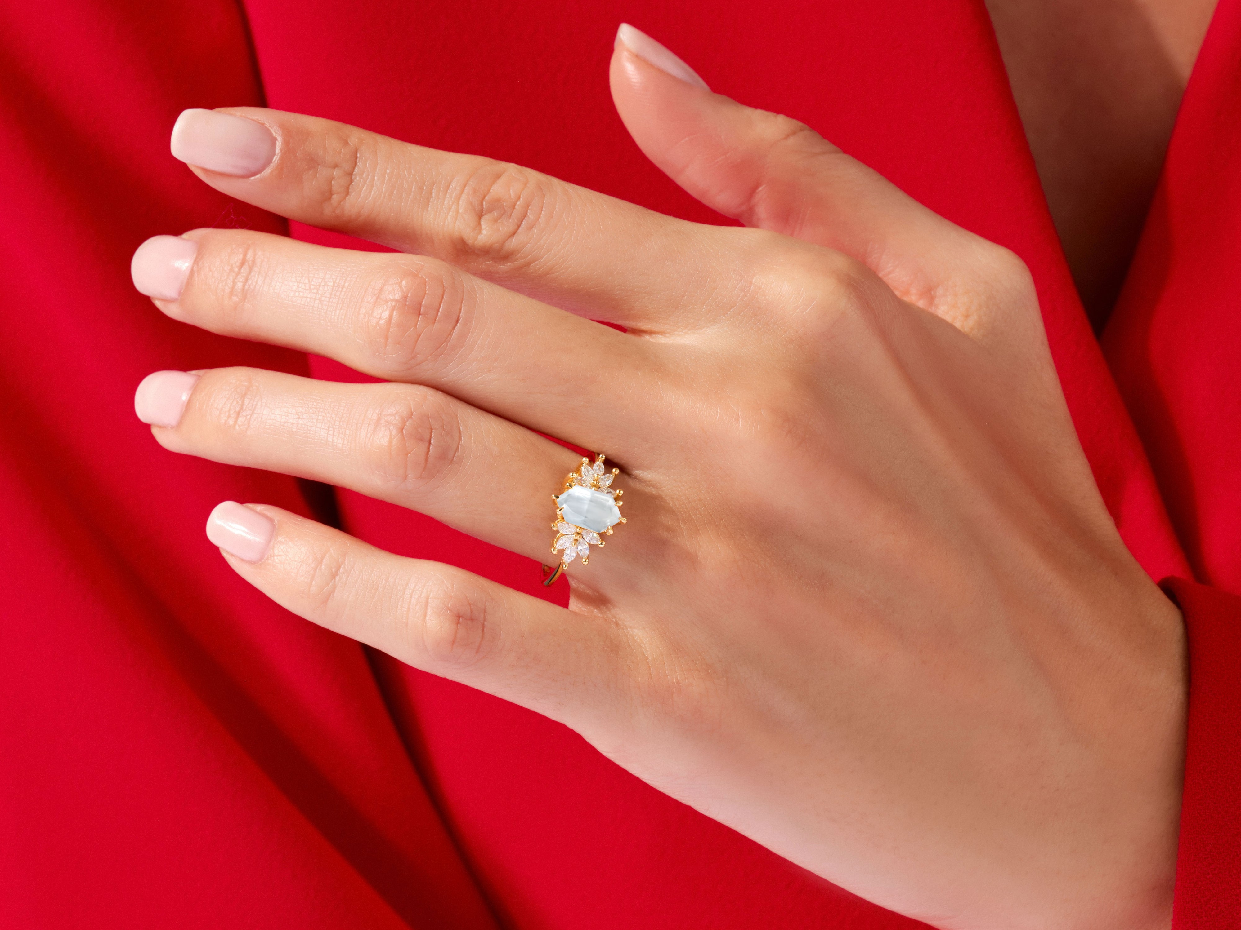 Gold ring with aquamarine and diamonds on a hand
