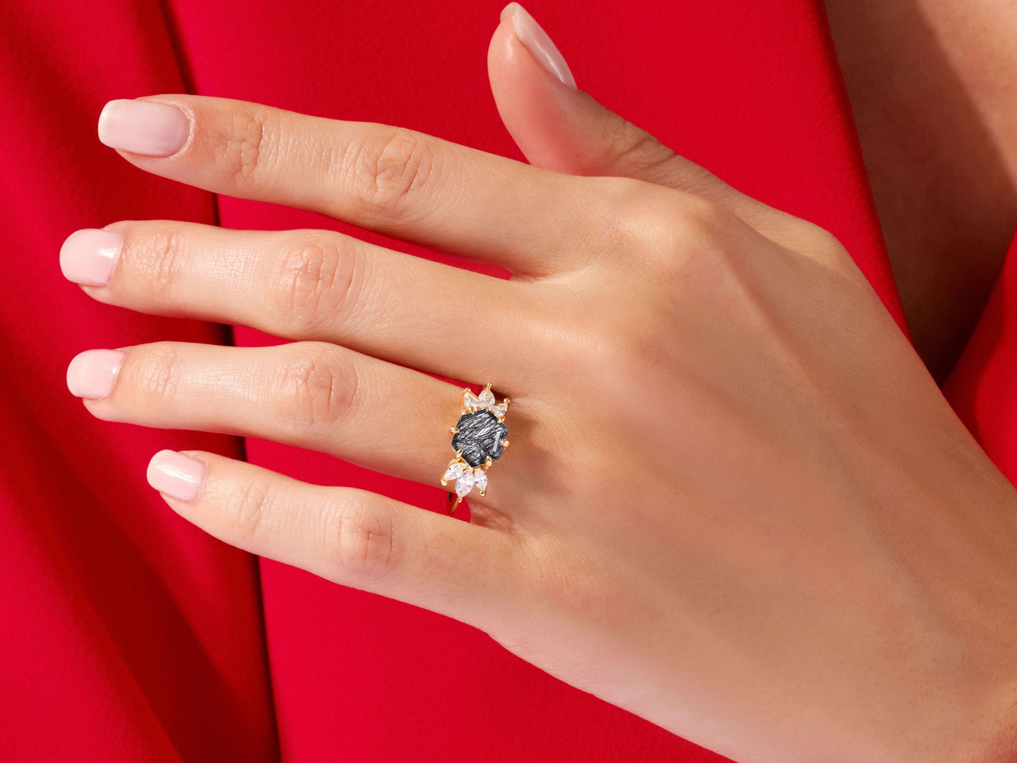 Gold ring with dark gemstone and diamonds on a hand