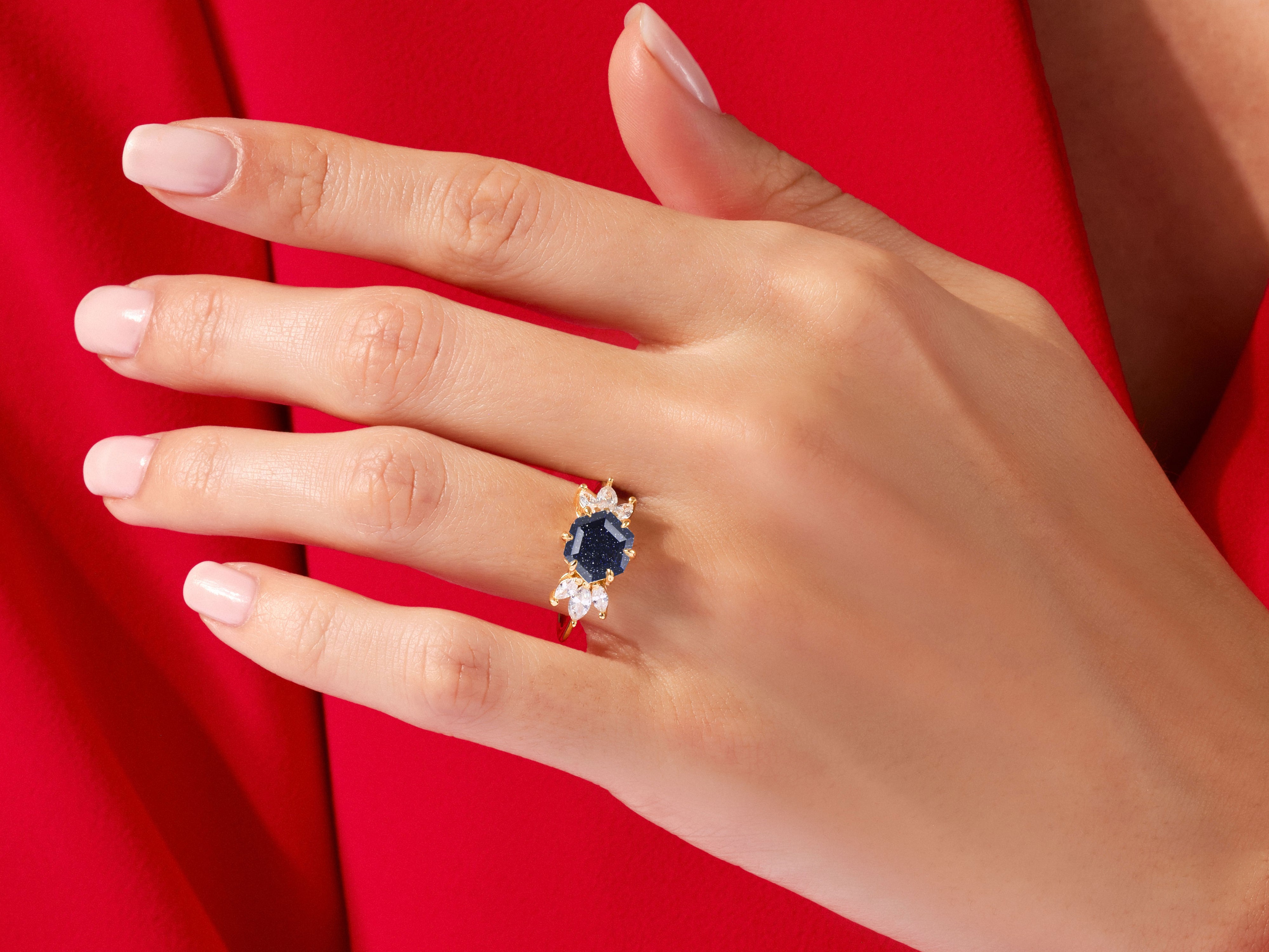 Gold ring with dark blue gemstone and diamonds on a hand