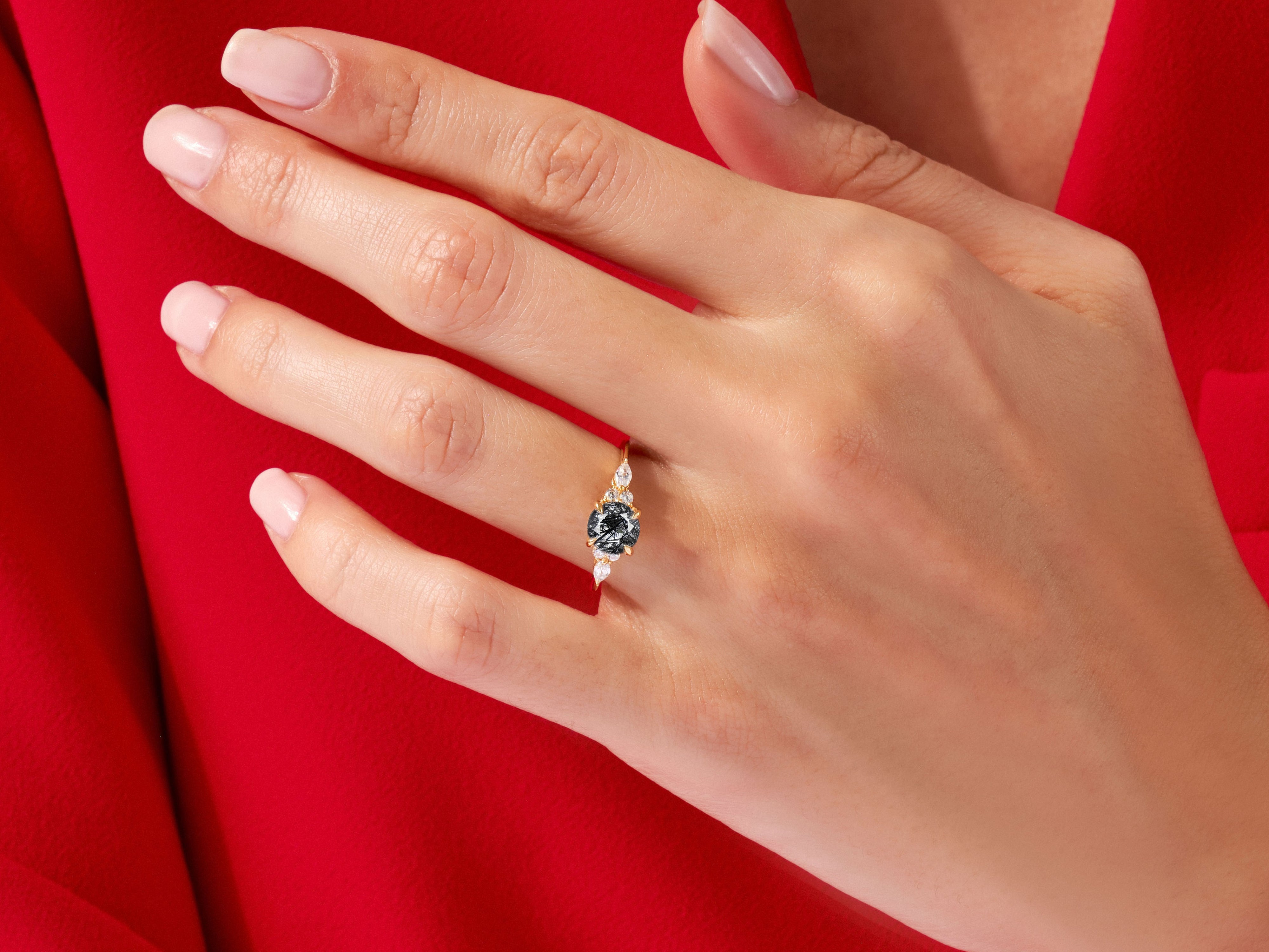 Elegant gold ring with dark gemstone and diamonds on a red background