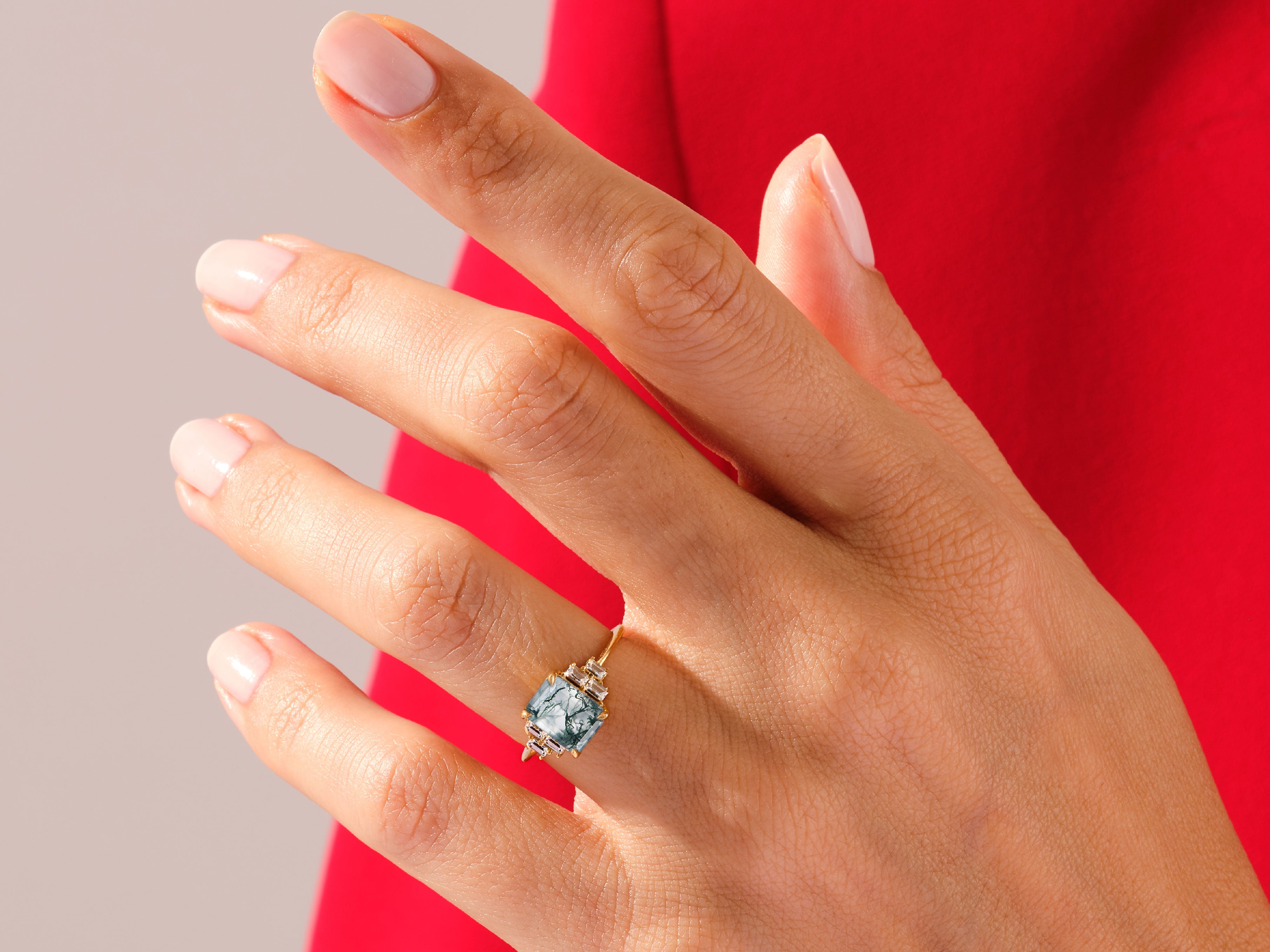 Emerald cut moss agate ring with diamonds on a hand