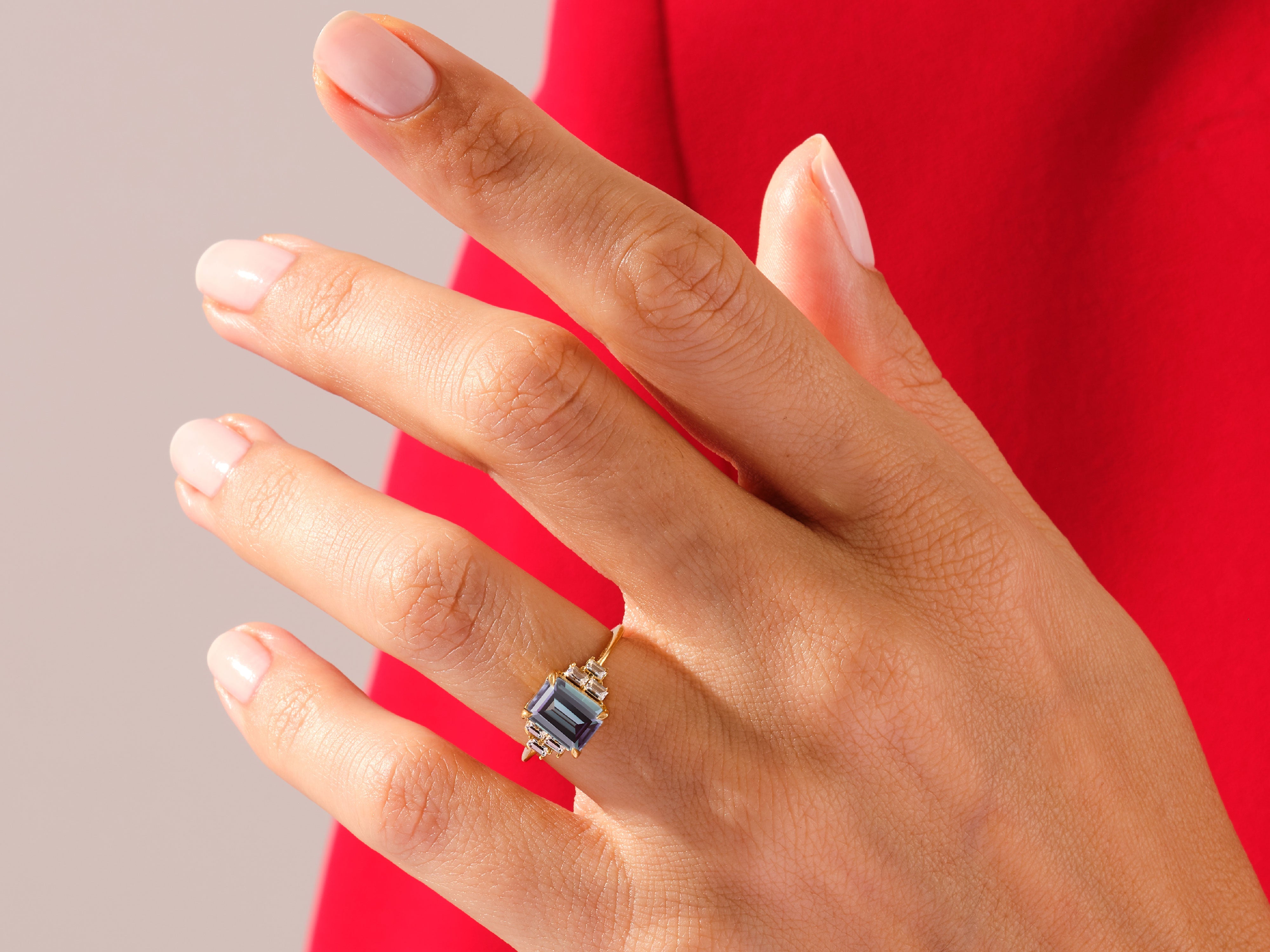 Emerald cut alexandrite ring with diamonds on a hand