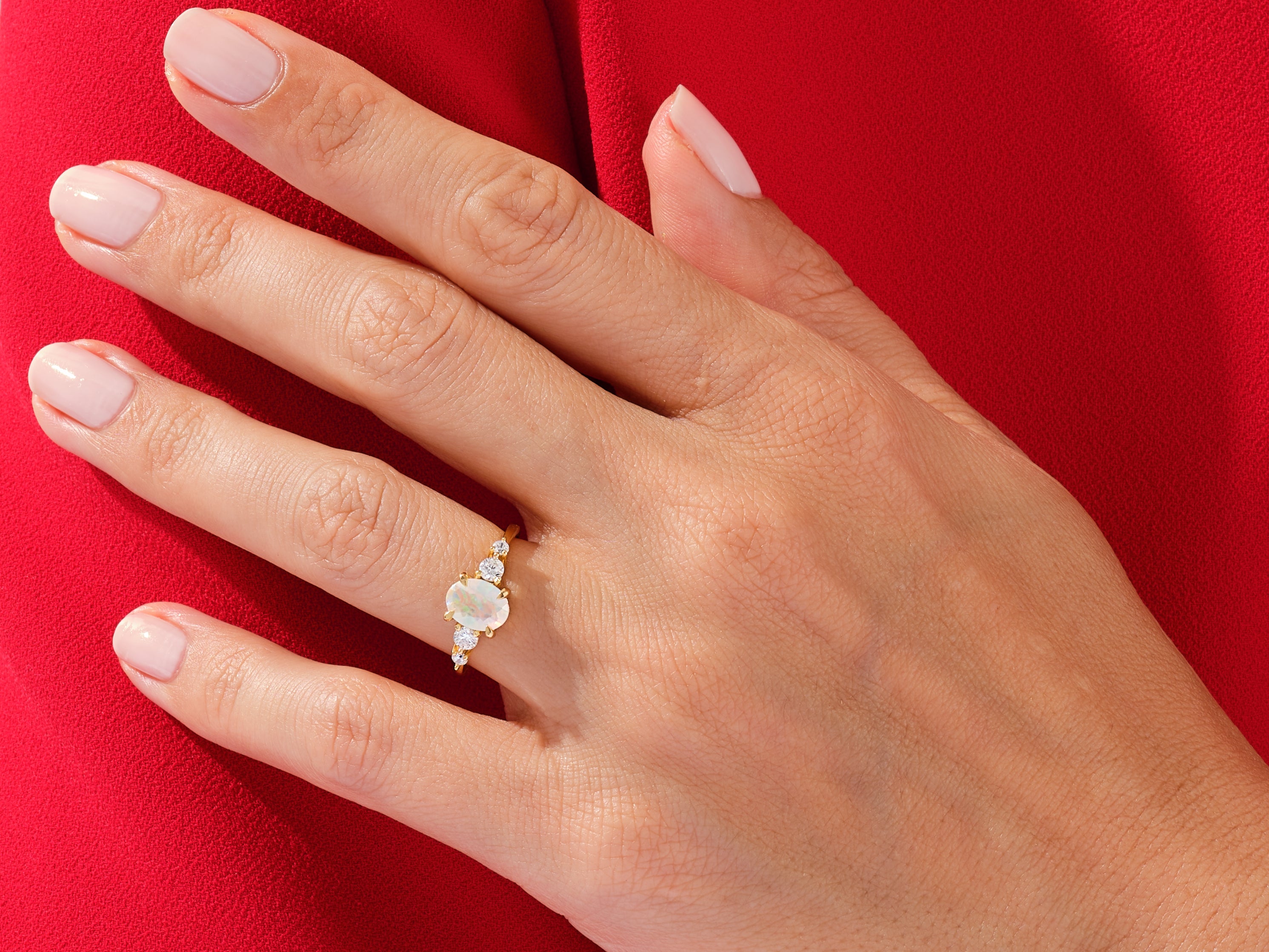 Gold opal and diamond ring on a hand