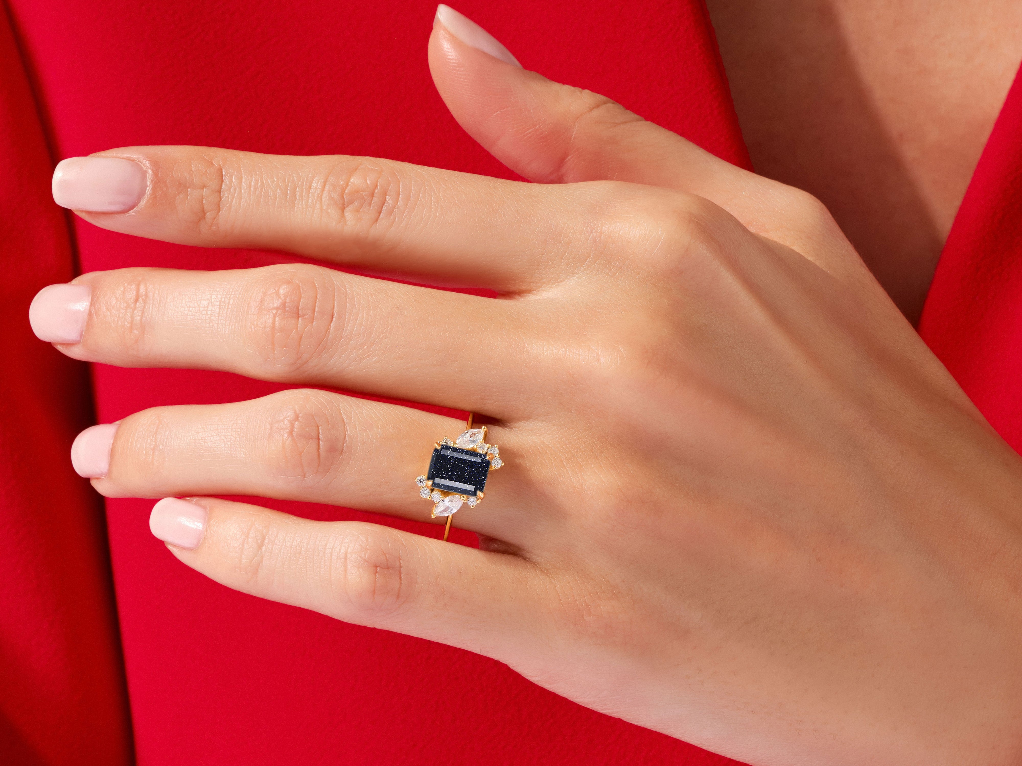 Gold ring with dark blue gemstone and diamonds on a red background