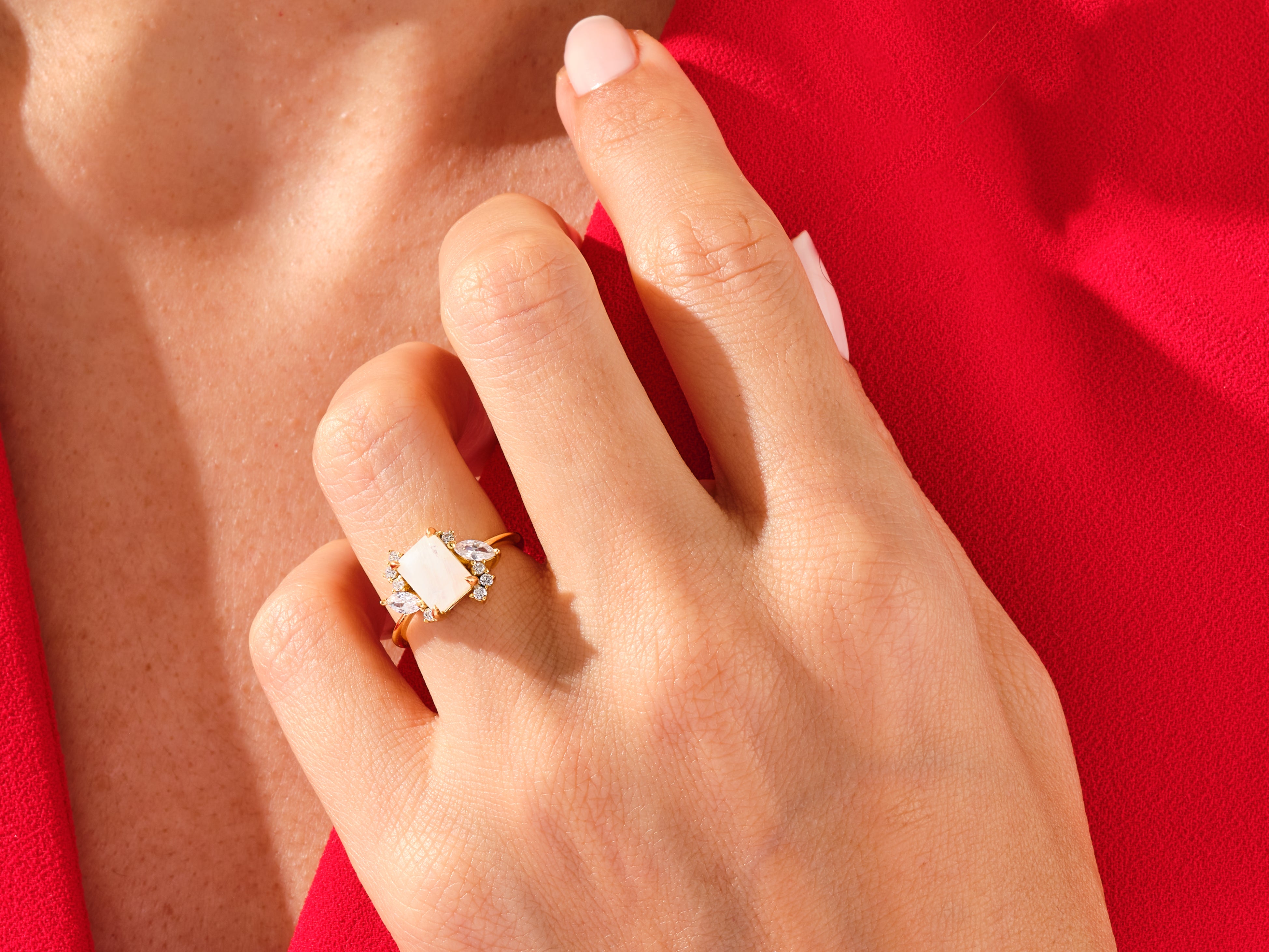 Elegant gold ring with rectangular gemstone and diamonds on hand