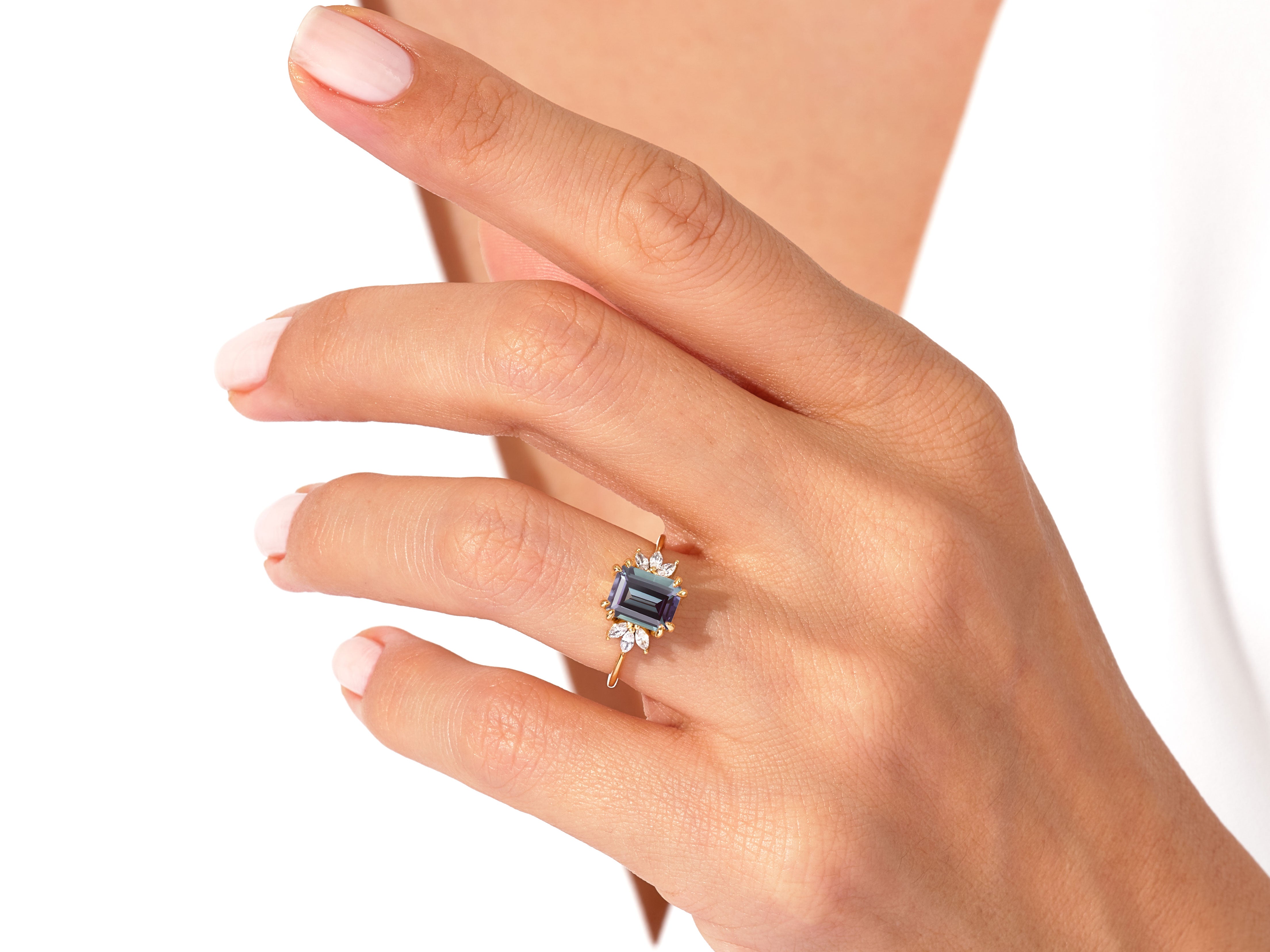Emerald cut sapphire ring with diamond accents on a woman's hand