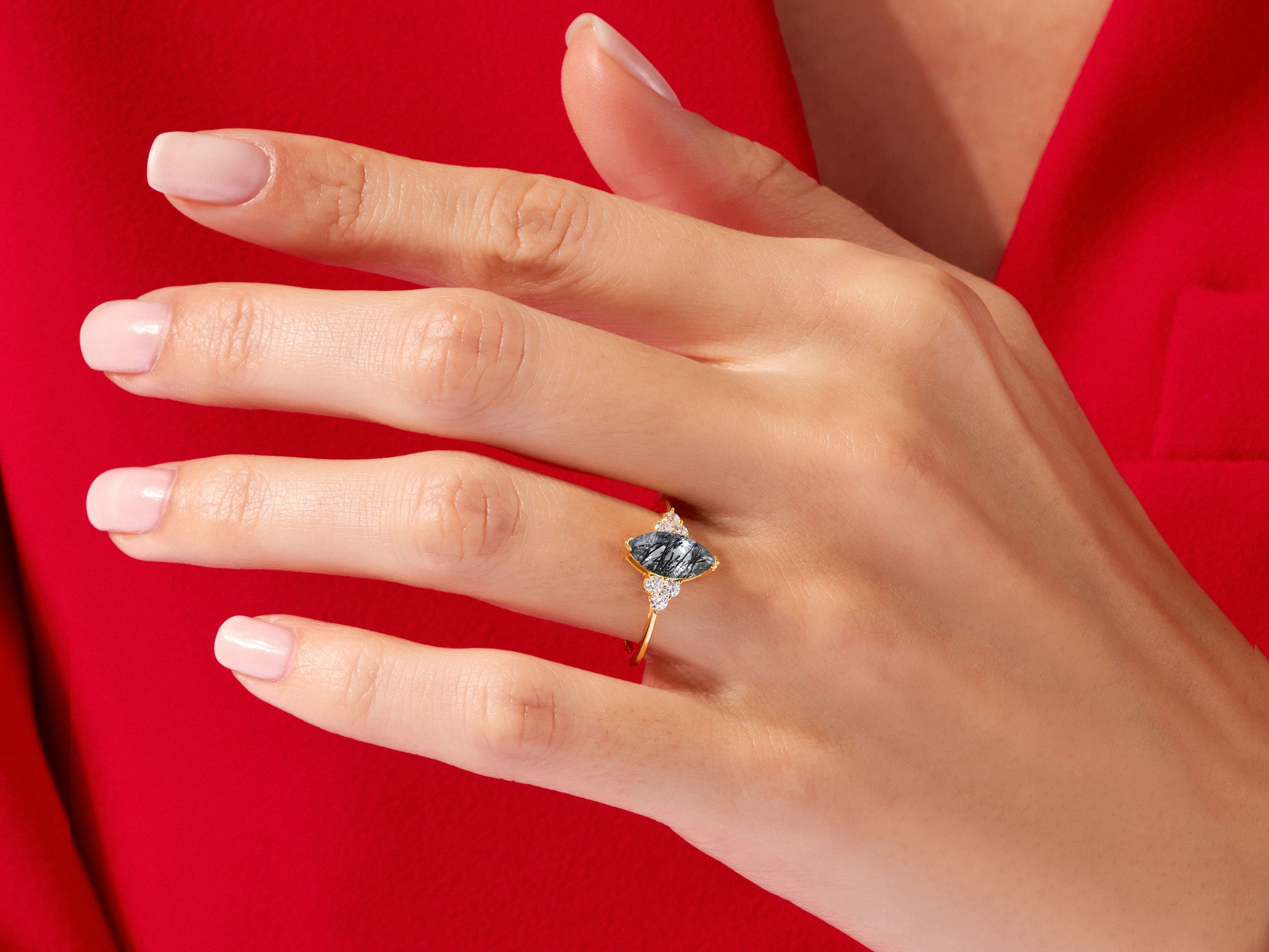 Gold ring with dark gemstone and diamonds on hand