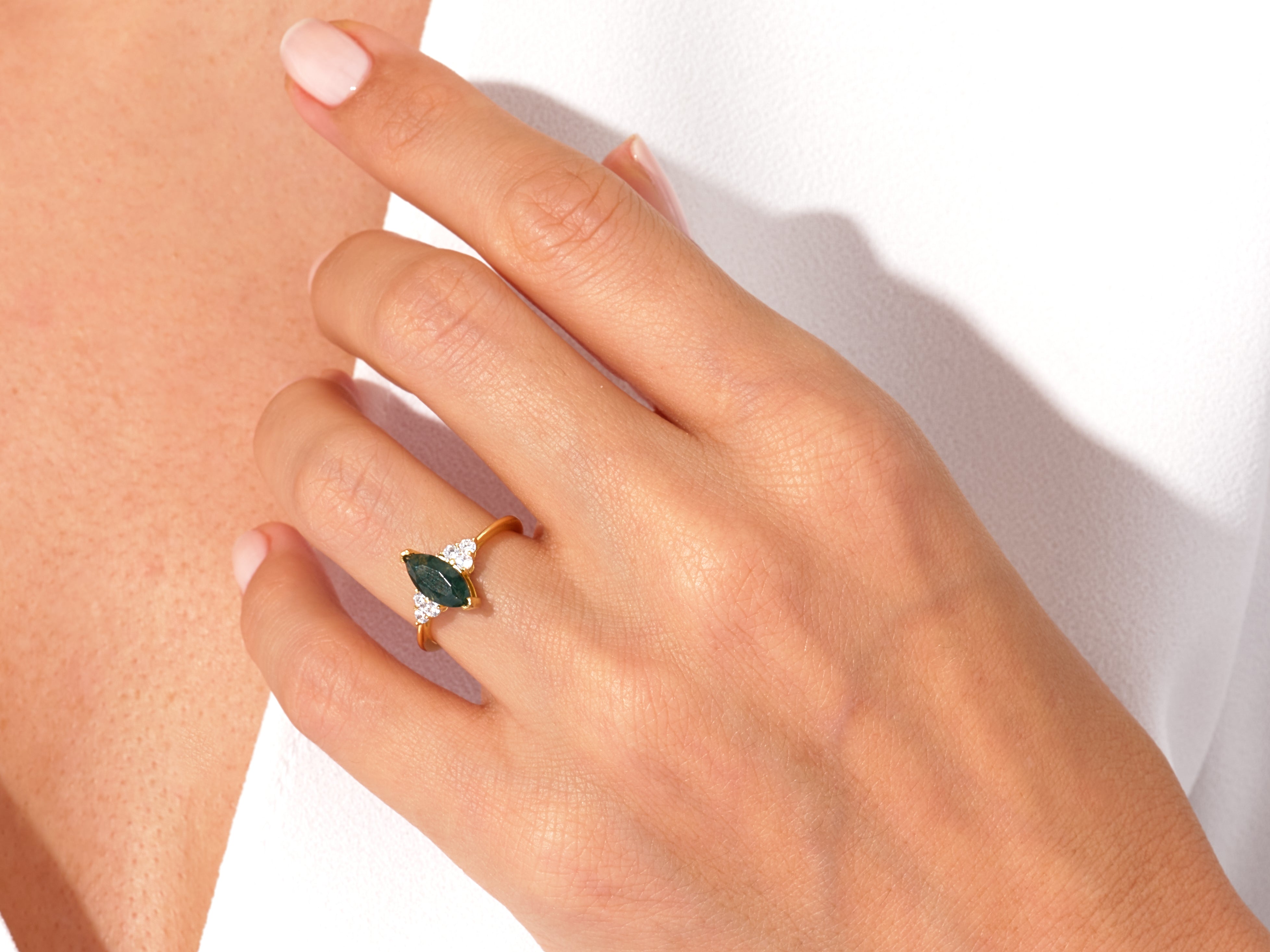 Gold marquise ring with green stone and diamonds on hand