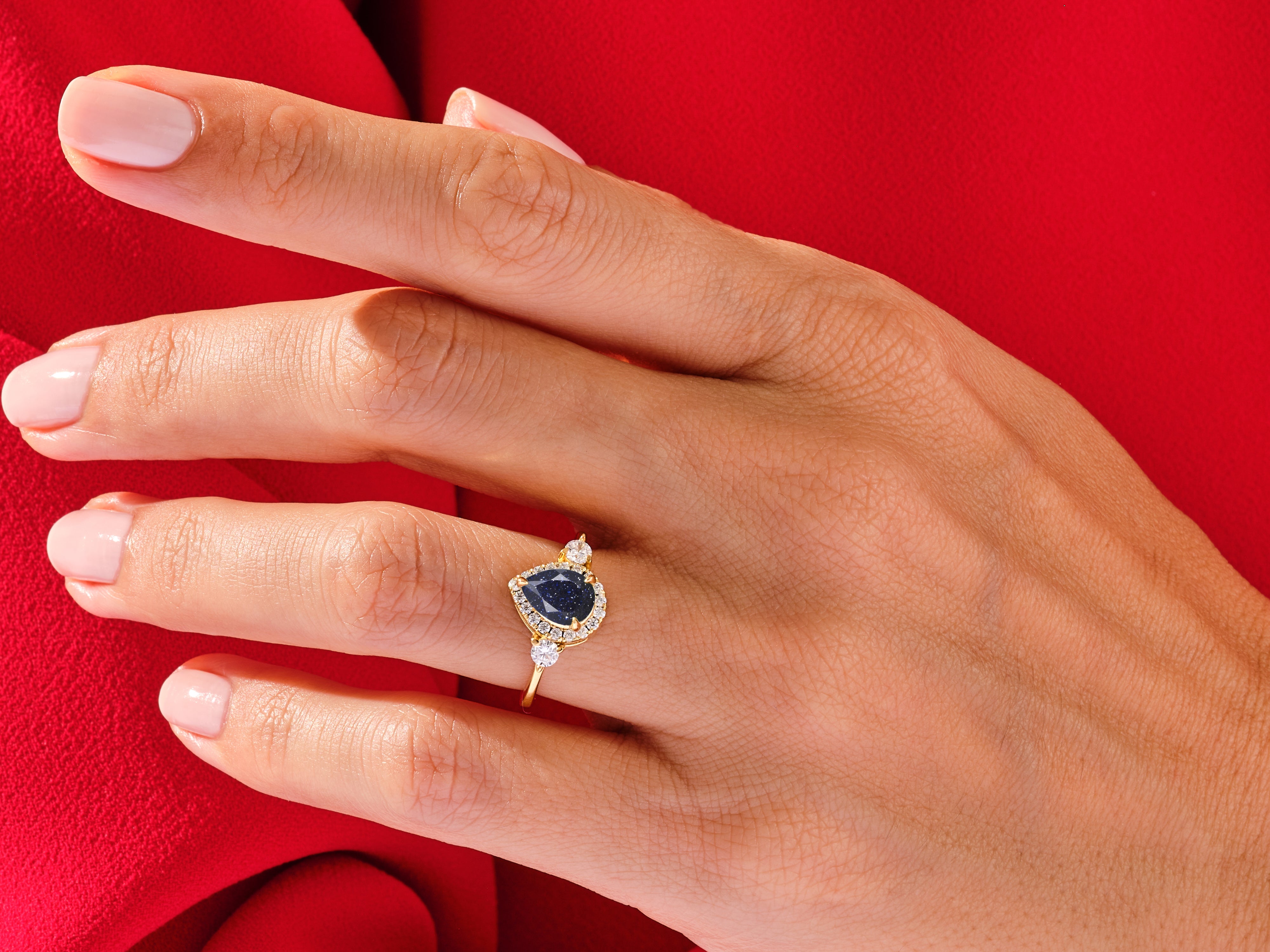 Gold ring with blue gemstone and diamonds on hand