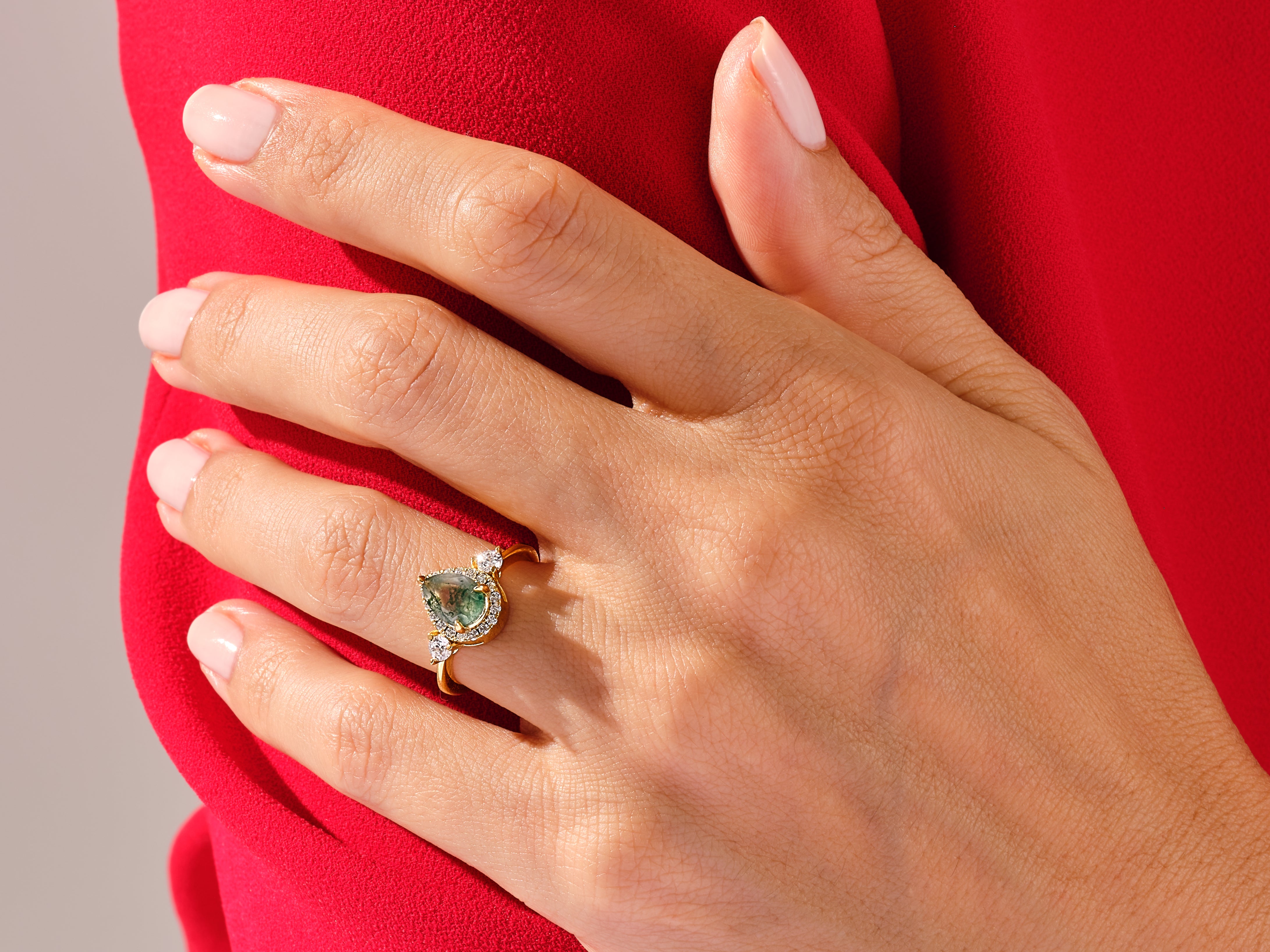 Gold ring with green gemstone and diamonds on hand