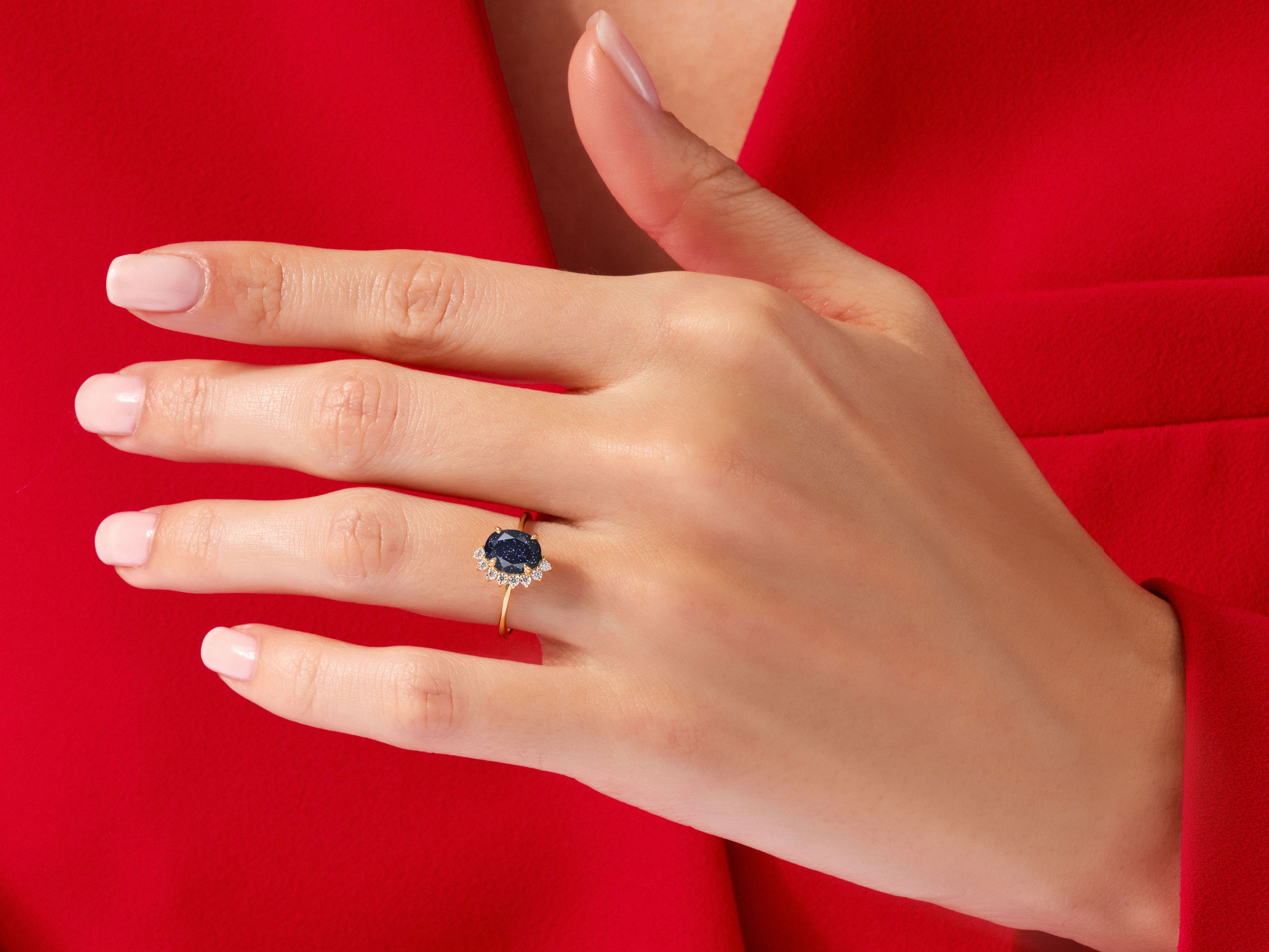 Gold ring with dark blue gemstone and diamonds on hand