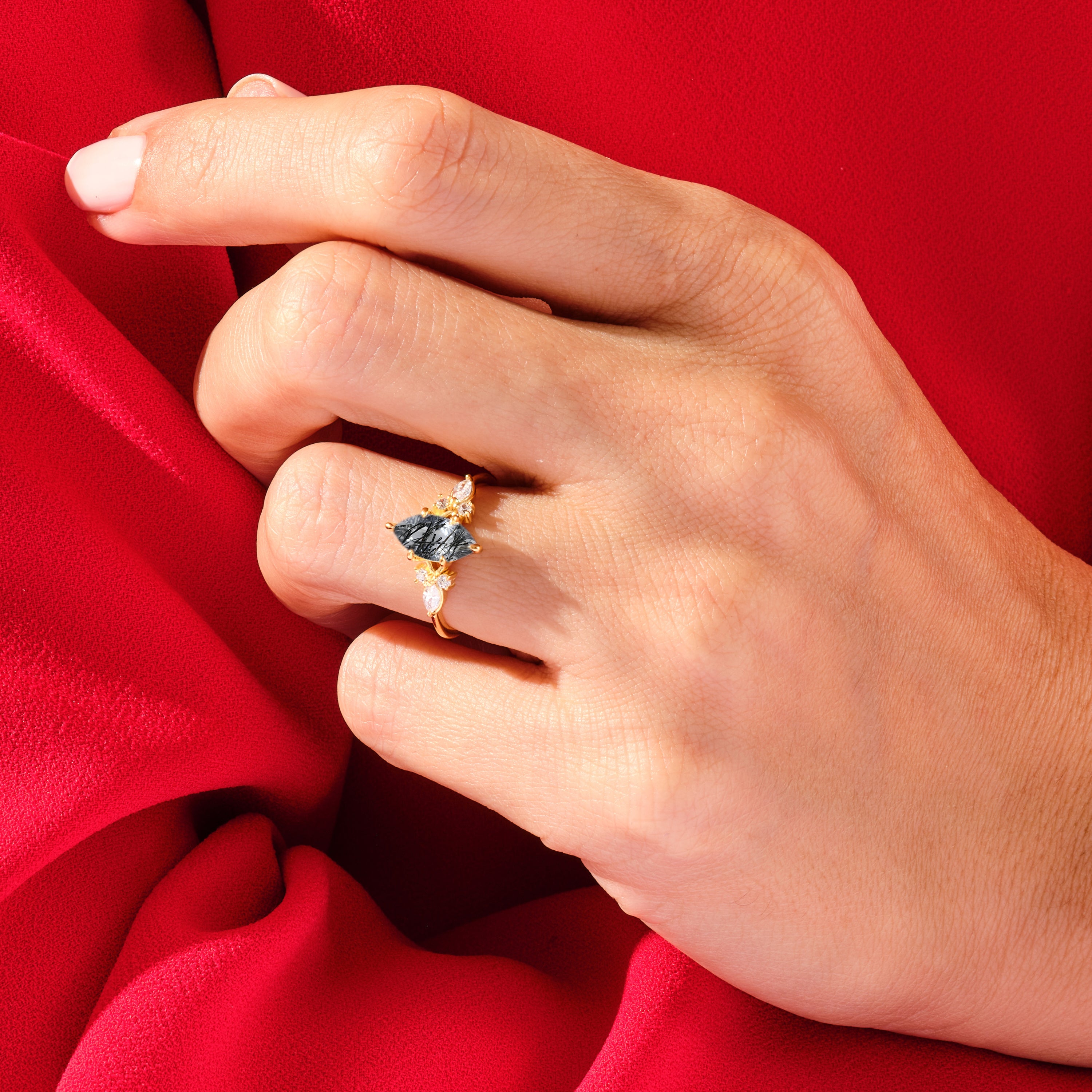 Gold ring with dark gemstone and diamonds on hand