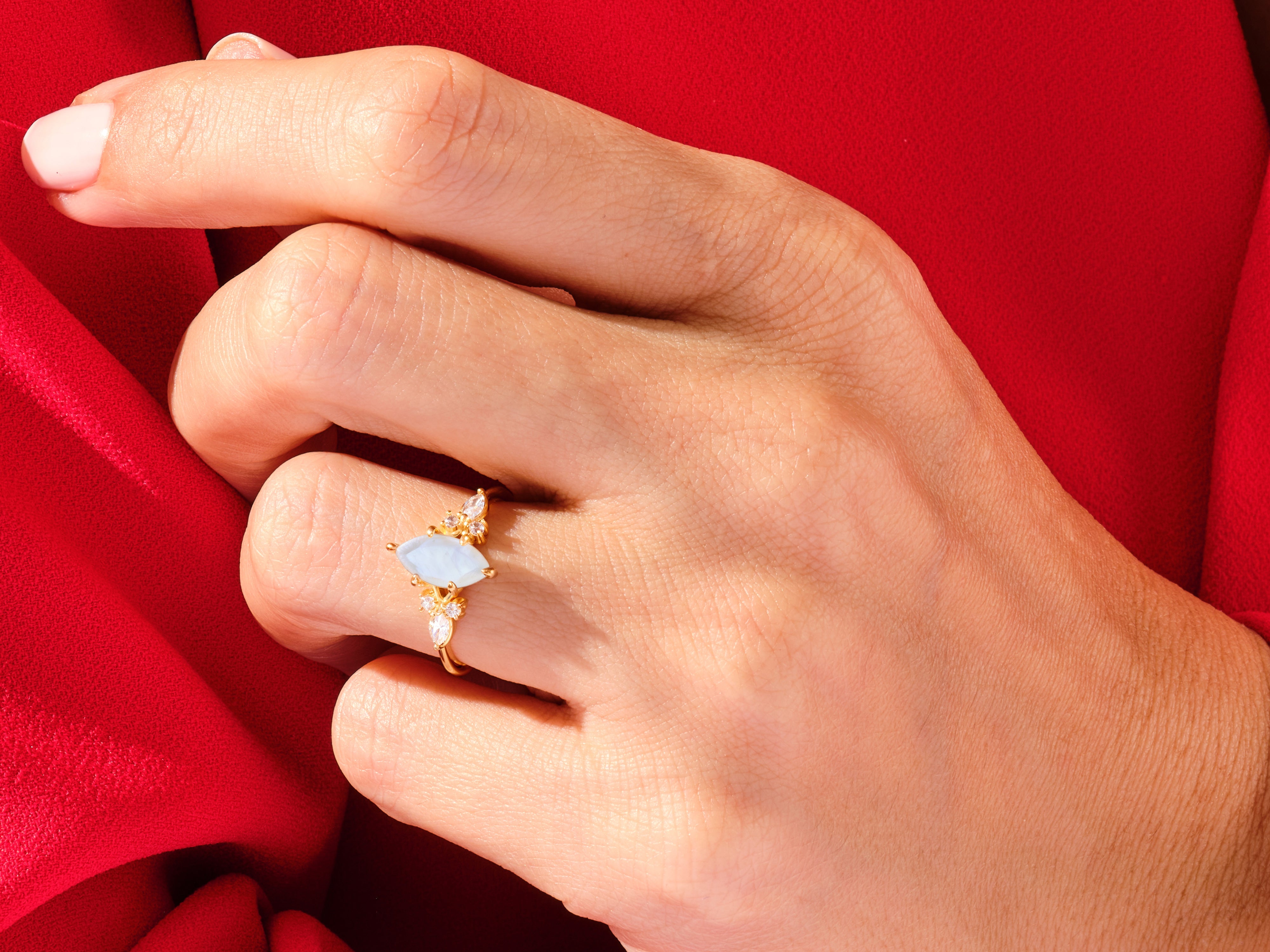 Gold ring with blue gemstone and diamonds on hand